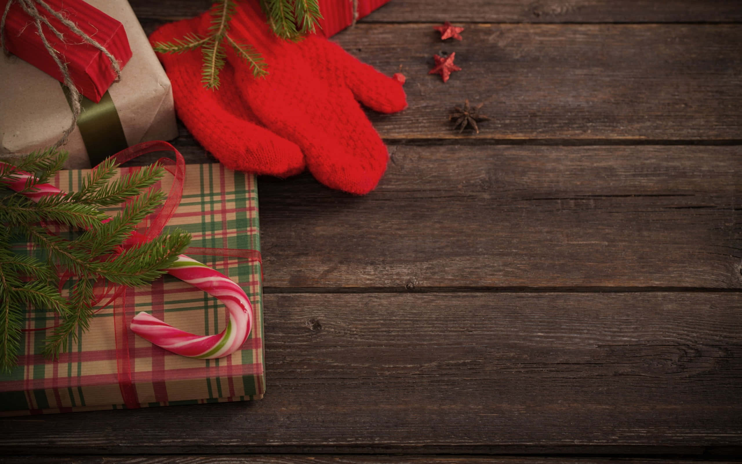 Mittens 桌布 壁紙 — 聖誕禮物、拐杖糖和紅色手套放在質樸的深色木桌上，搭配松枝和八角。