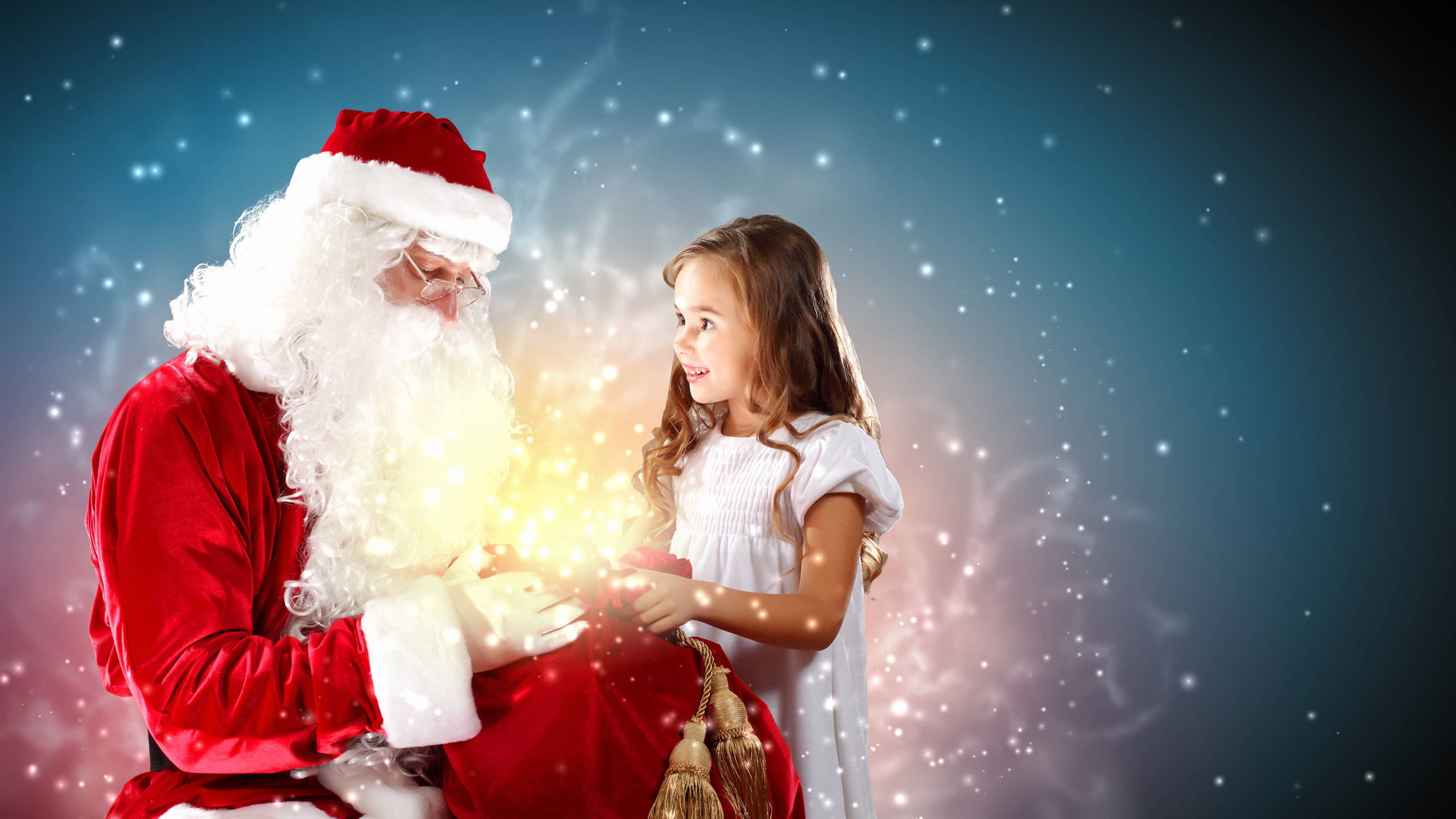 Santa Claus 桌布 壁紙 — 聖誕老人在閃爍的藍色背景前，將一份發光的禮物遞給一個微笑的女孩。