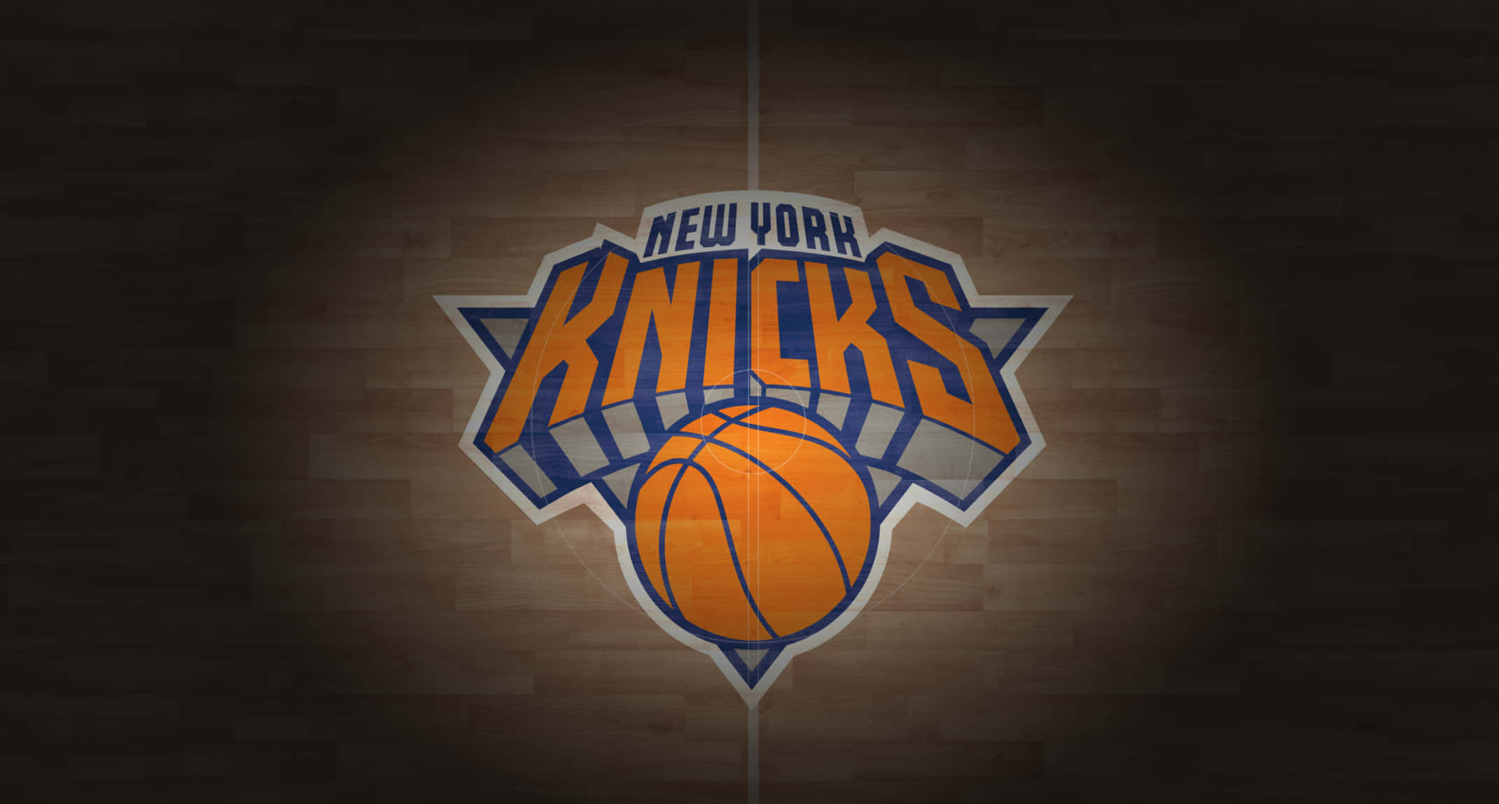 Knicks 桌布 壁紙 — 聚光燈照亮了木製籃球場地板中央的紐約尼克隊標誌。