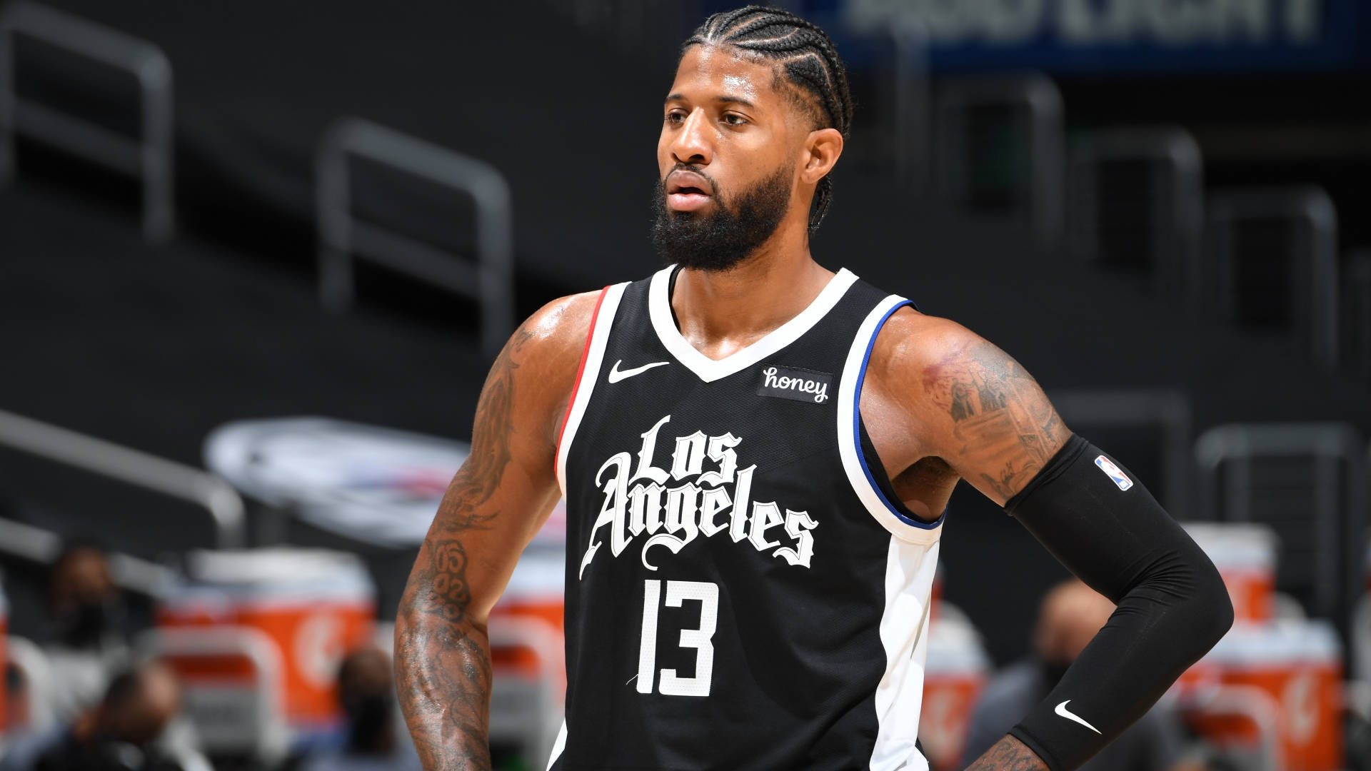 George 桌布 壁紙 — 職業籃球運動員 Paul George 身穿黑白洛杉磯球衣，專注地站在球場上，紋身清晰可見。