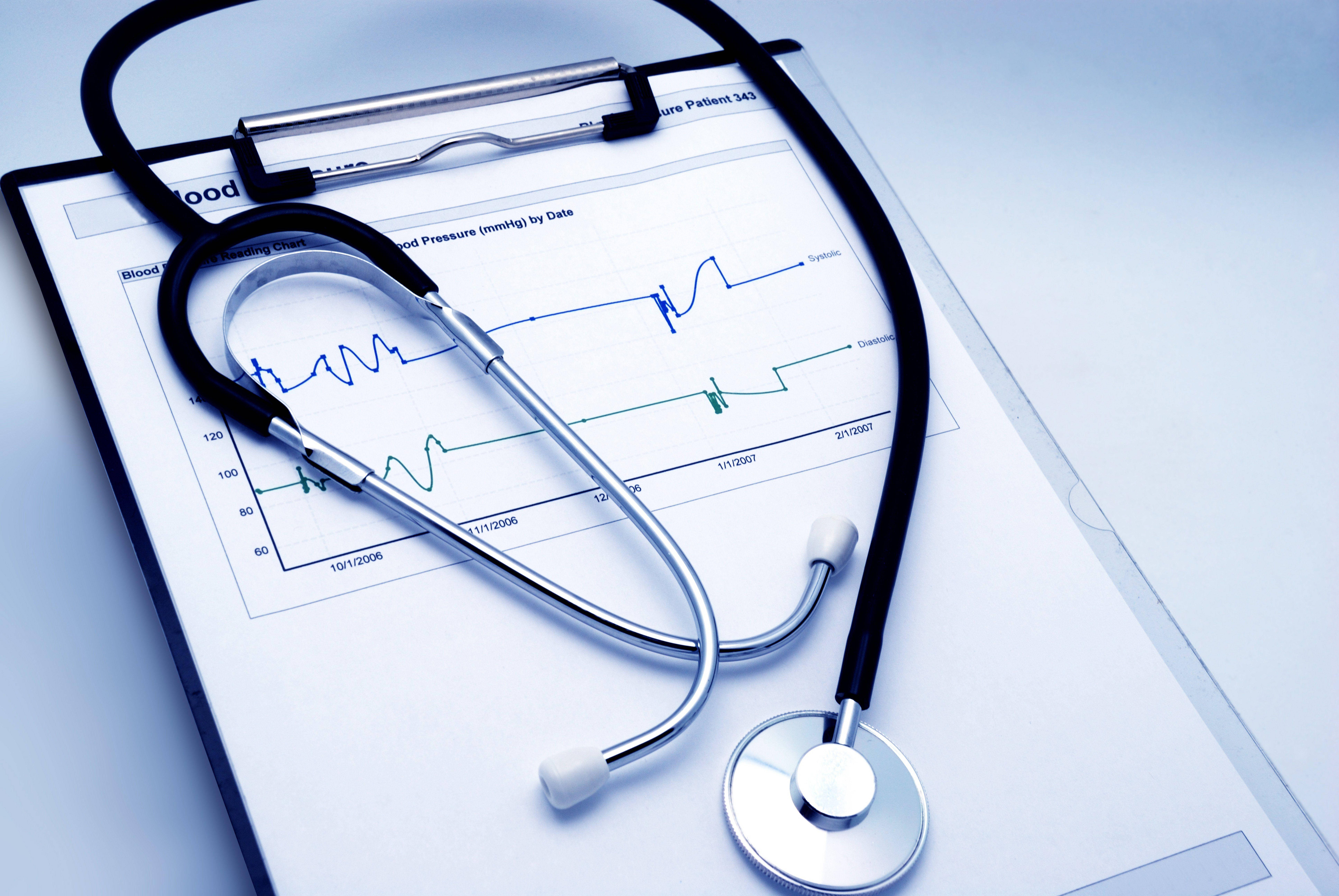 Stethoscope 桌布 壁紙 — 聽診器放在一個帶有血壓圖表的剪貼板上，以冷藍色調顯示病人數據。