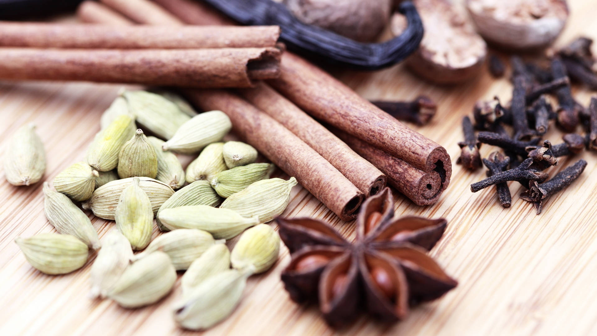 Spice 桌布 壁紙 — 肉桂棒、荳蔻莢、八角茴香和丁香等芳香香料在木質表面上的特寫。