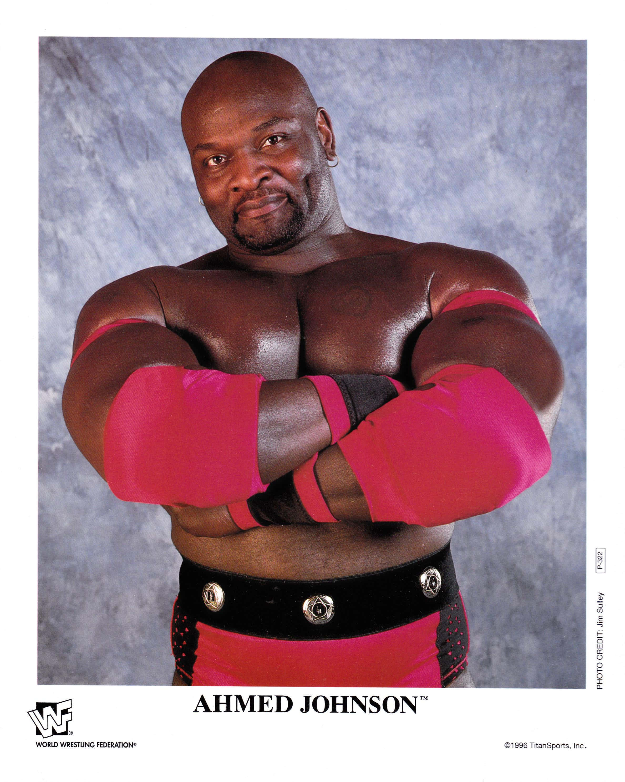 摔角 桌布 壁紙 — 肌肉發達的摔角手 Ahmed Johnson 在紋理灰色背景前自信地交叉雙臂擺姿勢。