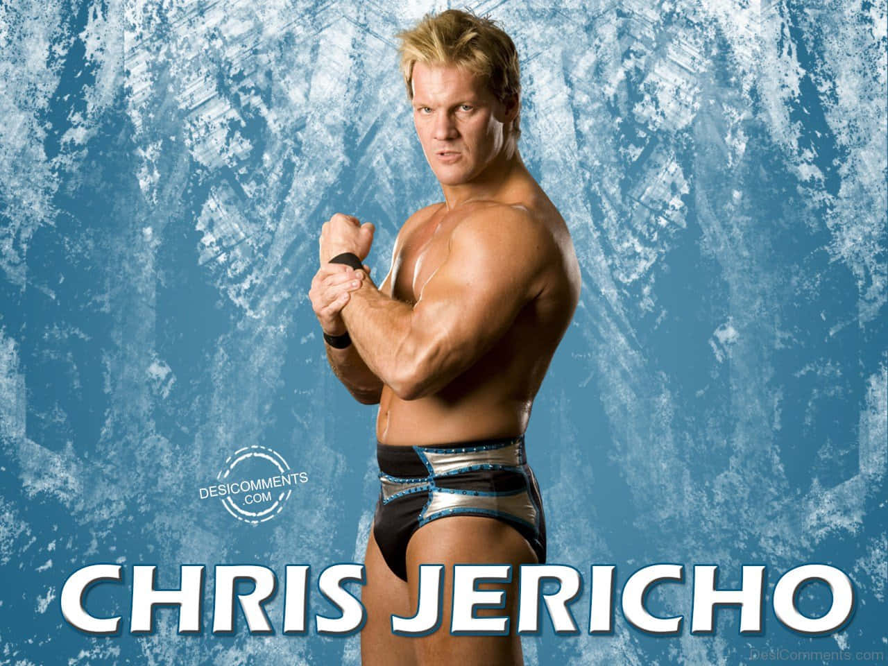 WWE 桌布 壁紙 — 肌肉發達的摔角手 Chris Jericho 穿著閃亮摔角短褲，在帶有紋理的藍色背景前自信地擺姿勢。