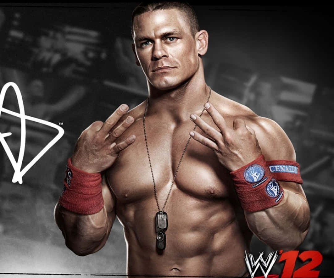 約翰·希南 桌布 壁紙 — 肌肉發達的摔角手約翰·希南（John Cena）赤裸上身，佩戴紅色腕帶和狗牌，以黑暗模糊的摔角場地為背景擺姿勢。