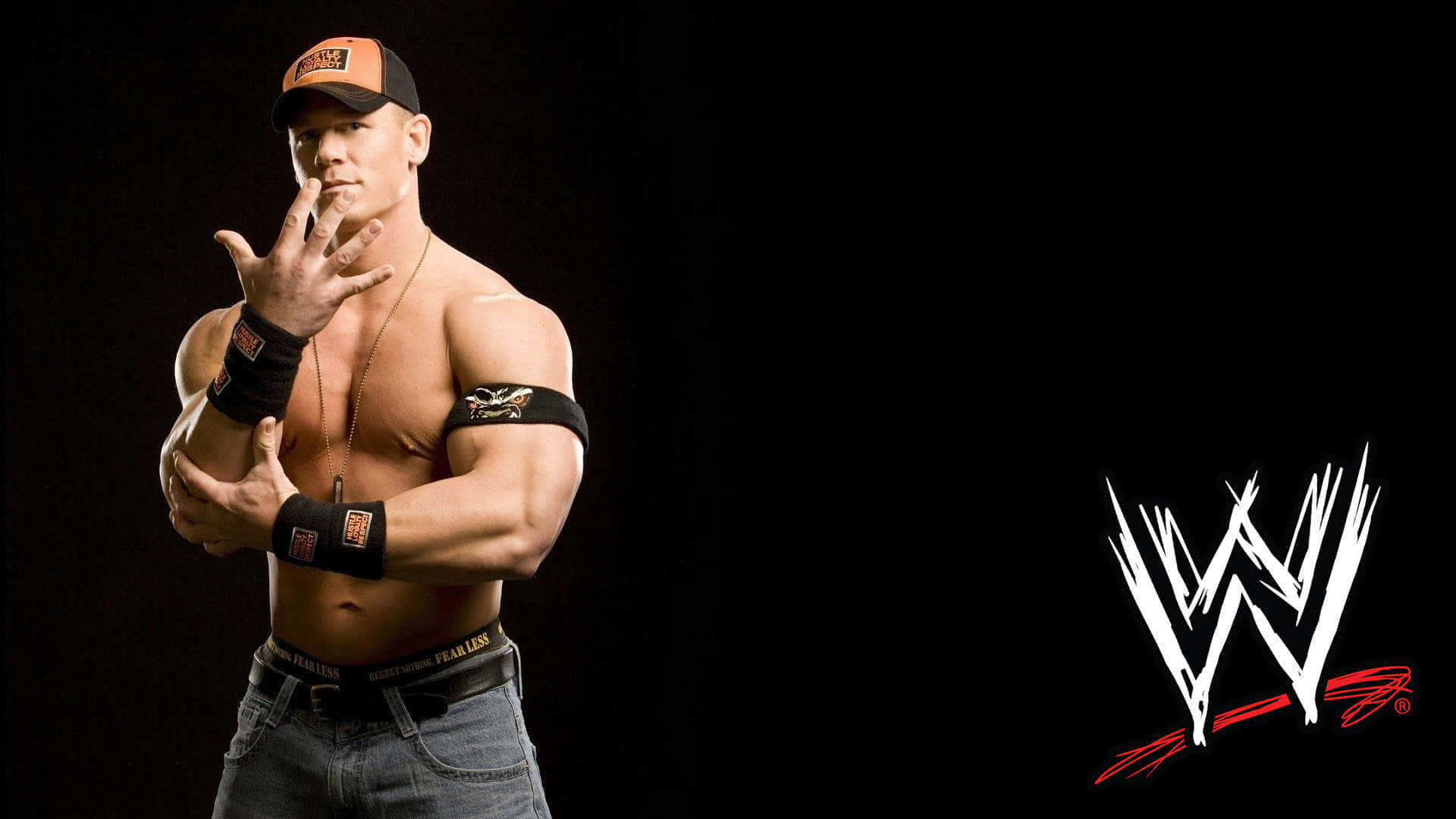 WWE 桌布 壁紙 — 肌肉發達的摔角手約翰·希南戴著黑色和橙色帽子，在深色背景前自信地擺姿勢，帶有WWE標誌。