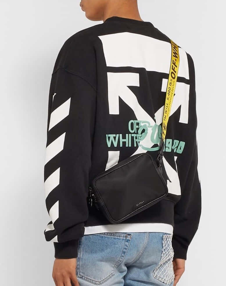 Off White 桌布 壁紙 — 背面視角，一個人穿著大膽的黑白圖案衛衣，帶有綠色文字，並背著黑色斜背包。