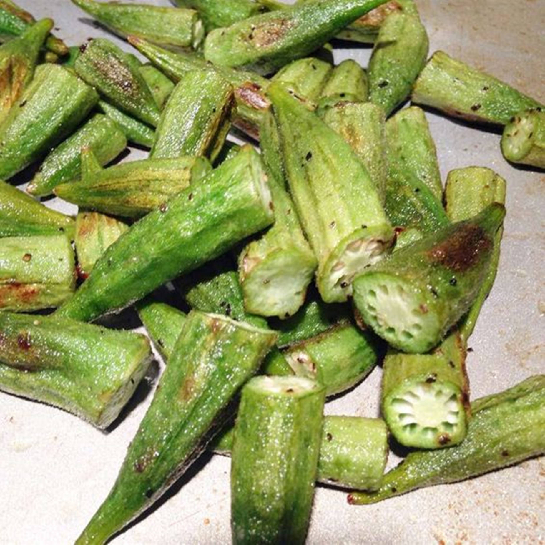 Healthy Food 桌布 壁紙 — 脆烤秋葵莢，邊緣焦黑，籽粒可見，置於淺色表面上。
