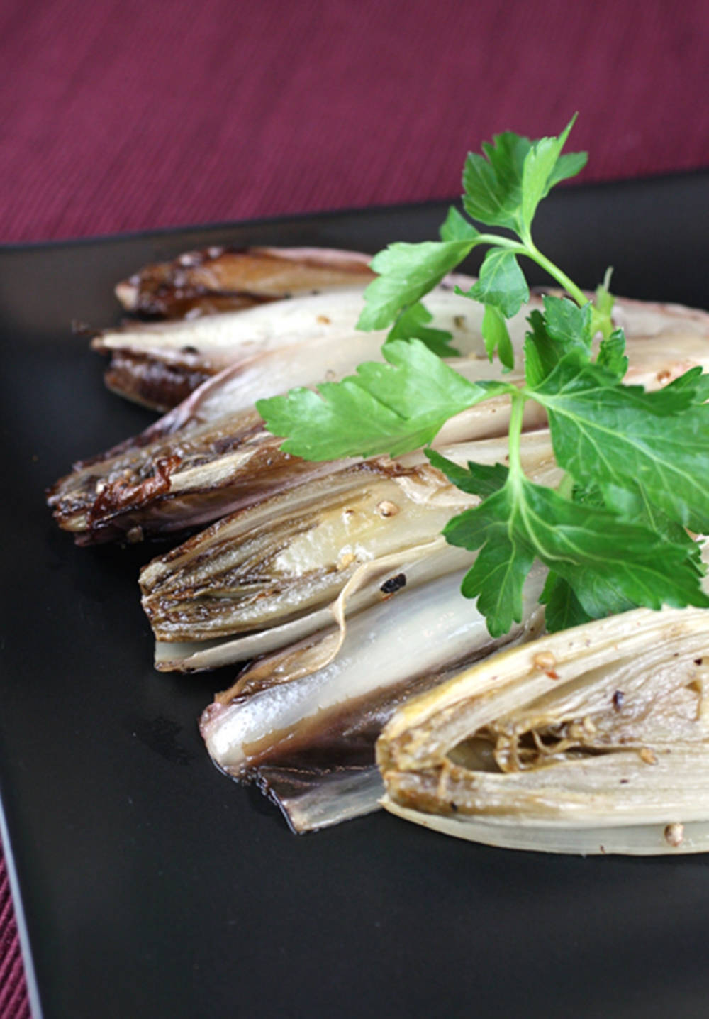 Food Photography 桌布 壁紙 — 脆烤菊苣葉，飾以新鮮歐芹，置於時尚黑色餐盤上，襯以深酒紅色背景。