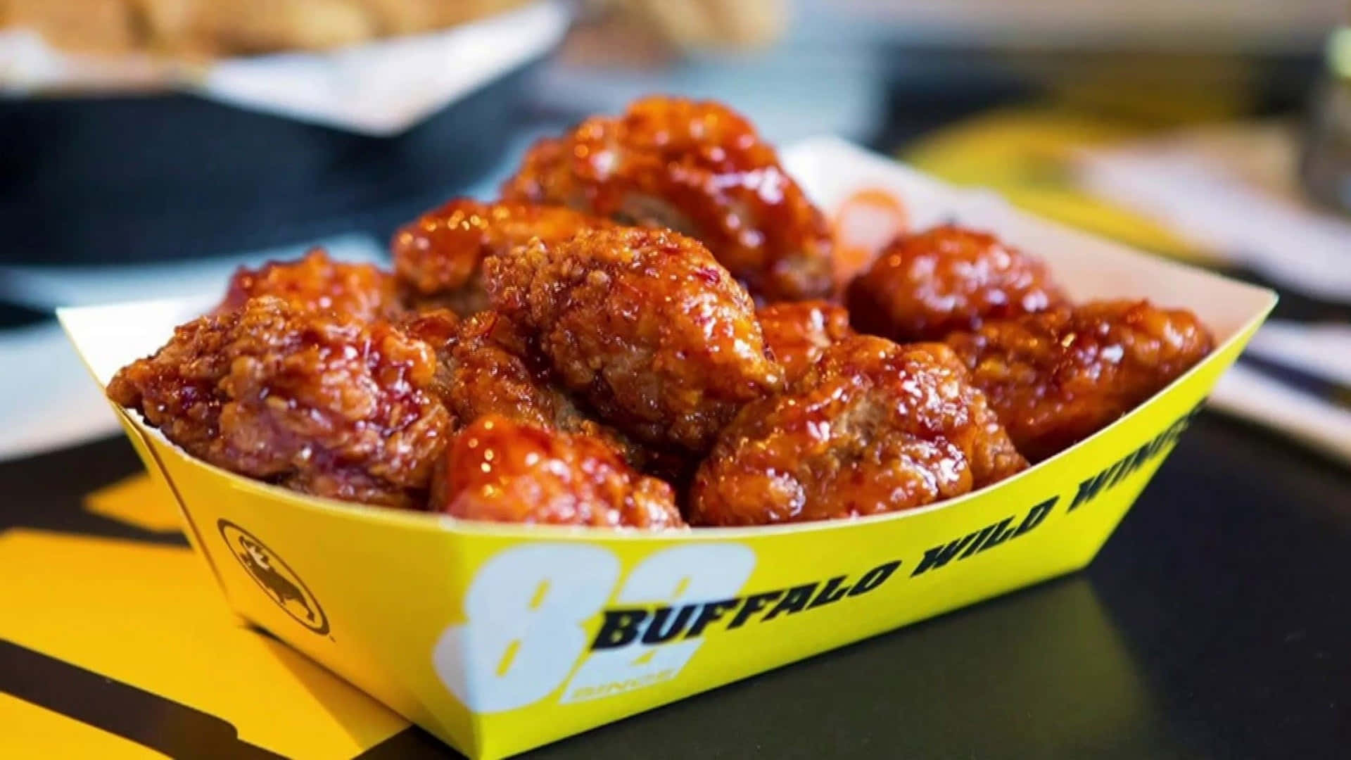 脆皮水牛城雞翅放在黃色的 Buffalo Wild Wings 紙托盤中。 — 水牛城辣雞翅 壁紙
