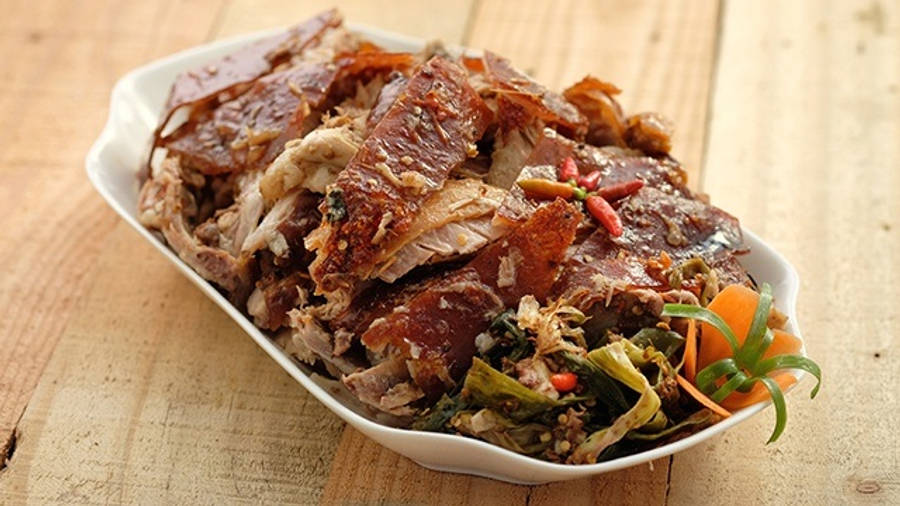 Pig 桌布 壁紙 — 脆皮烤豬肉搭配香草和紅蘿蔔，盛放在白色盤子中，置於鄉村風木桌上。