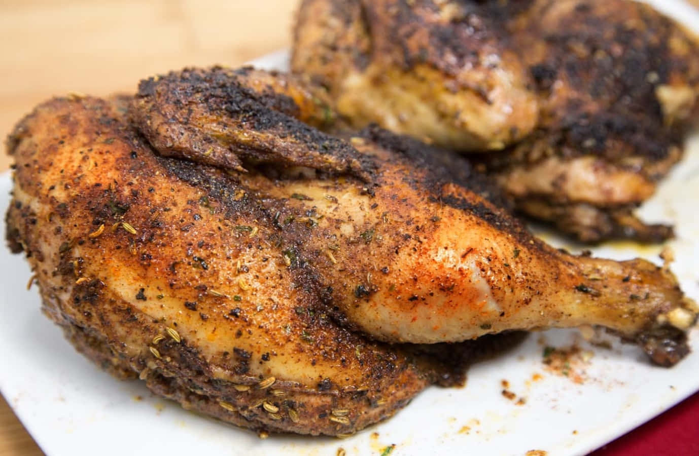 Blackened Chicken 桌布 壁紙 — 脆皮調味烤雞腿，在白色盤子上閃爍著香料光澤。