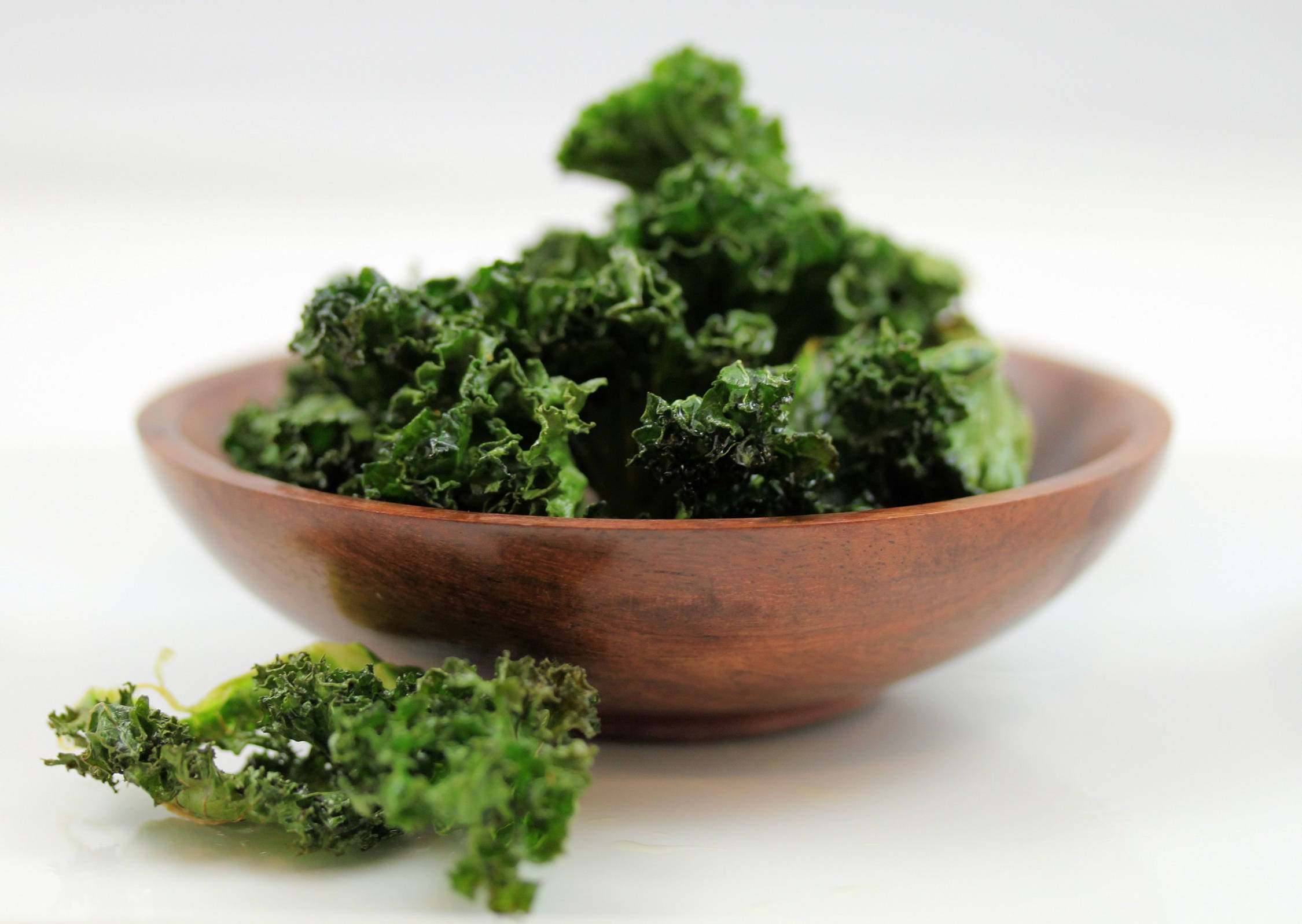 Vegetable 桌布 壁紙 — 脆綠羽衣甘藍脆片堆放在質樸的木碗中，襯以潔白背景。