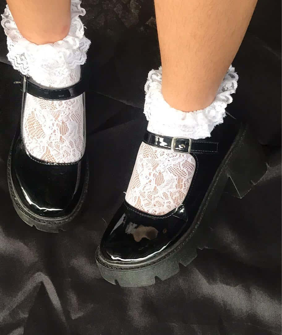 垃圾美學 桌布 壁紙 — 腳部特寫，穿著亮面黑色厚底瑪麗珍鞋和白色蕾絲襪，背景為深色布料。