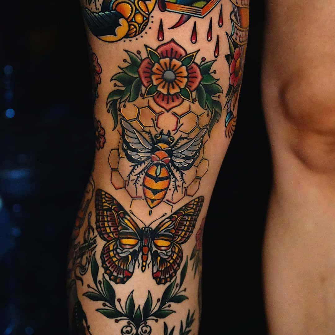 tattoos 桌布 壁紙 — 腿上充滿活力的傳統刺青，以蜜蜂、蝴蝶和花卉圖案為特色，輪廓大膽，色彩豐富。
