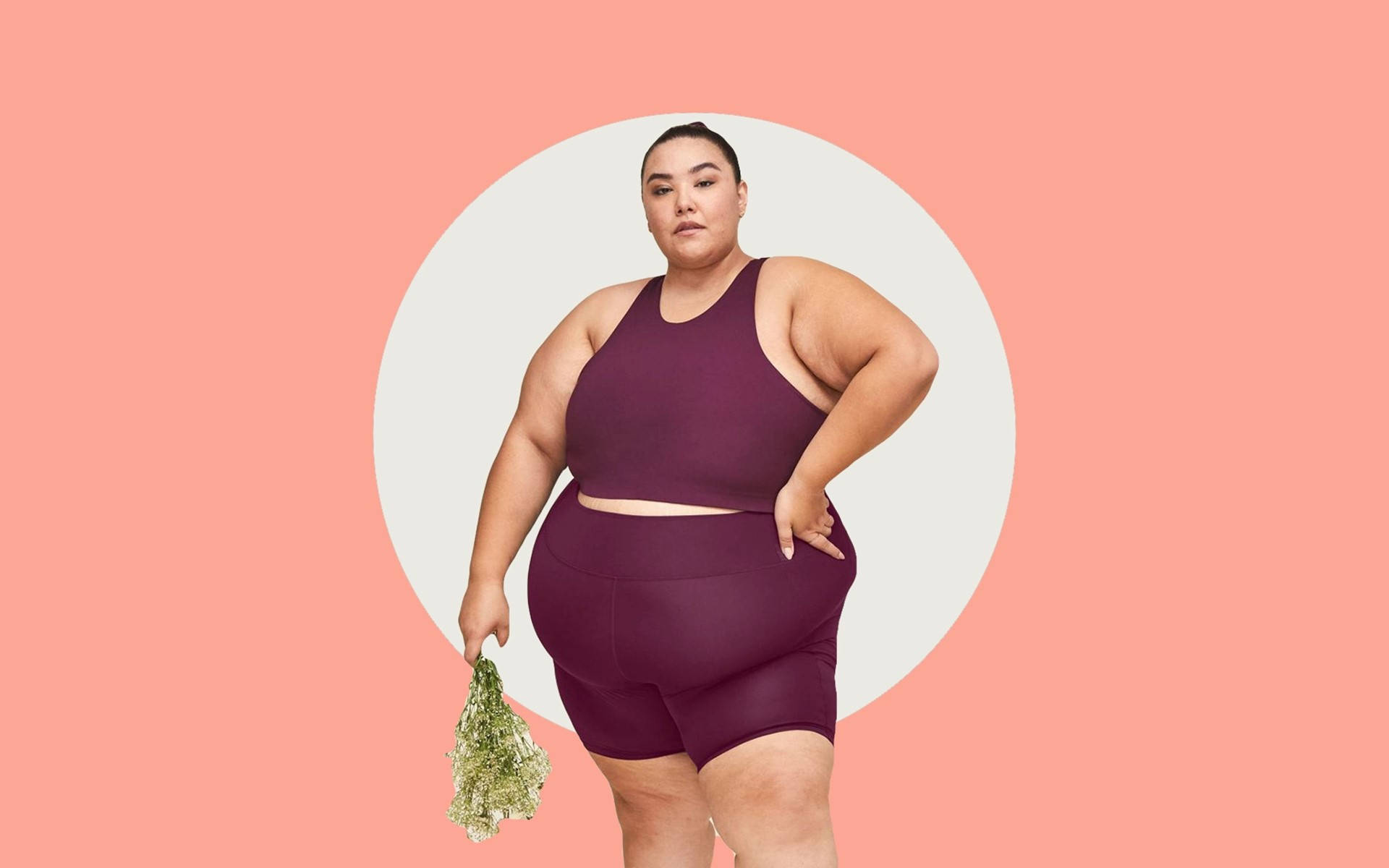 Fitness 桌布 壁紙 — 自信的女性穿著栗色運動服，在柔和的粉紅色背景上，手持乾燥草本植物，背景有一個白色圓形鏤空。