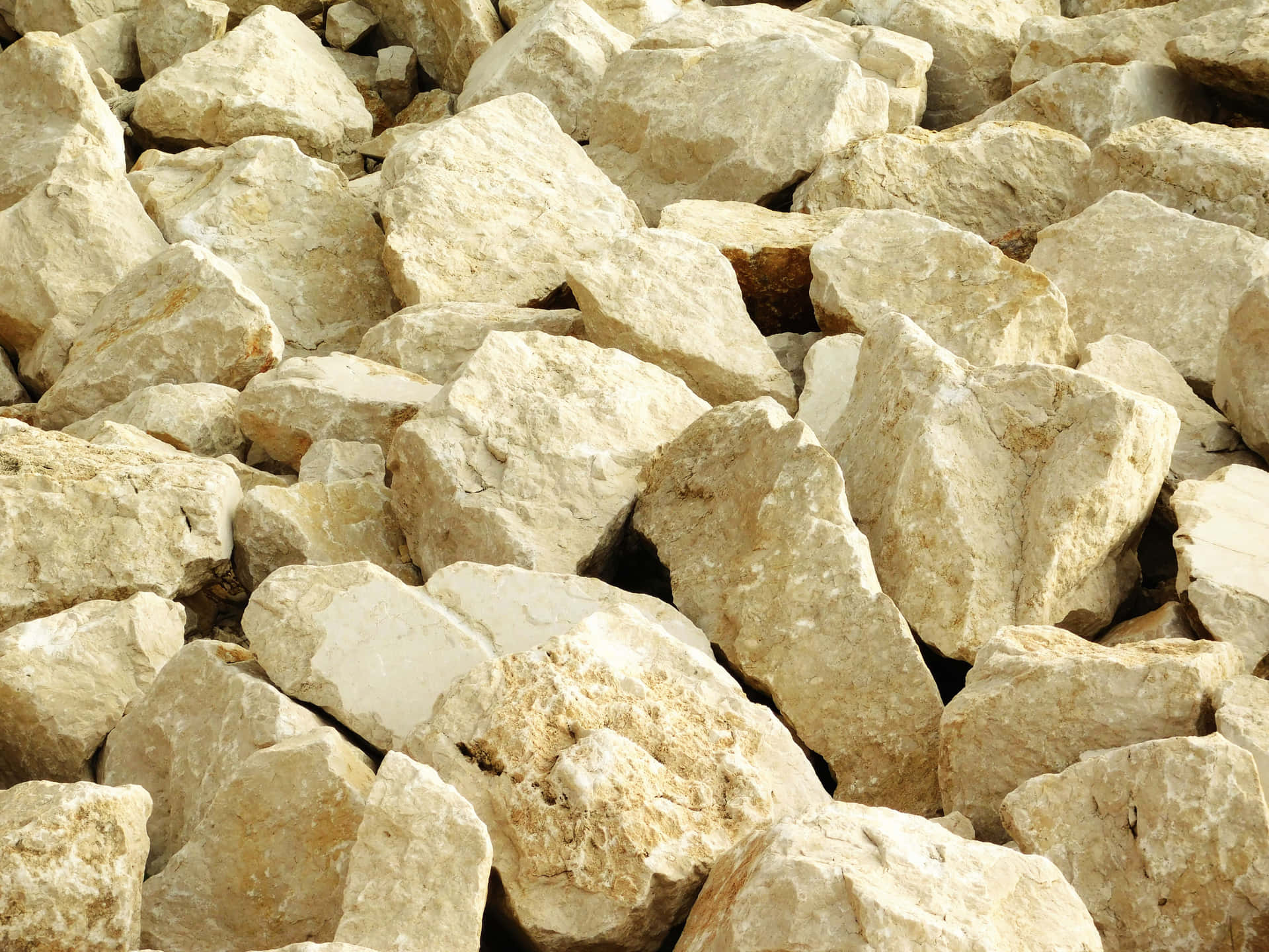 Stone texture 壁紙 — 自然陽光下堆疊在一起的粗糙米色和奶油色岩石的特寫。
