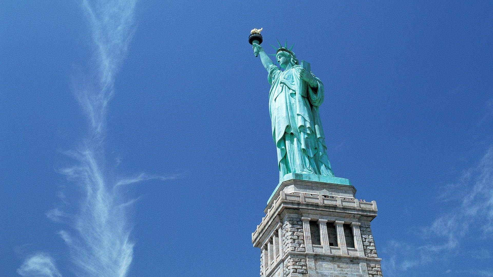 Statue Aesthetic 桌布 壁紙 — 自由女神像在充滿活力的藍天和縷縷白雲中高高聳立。