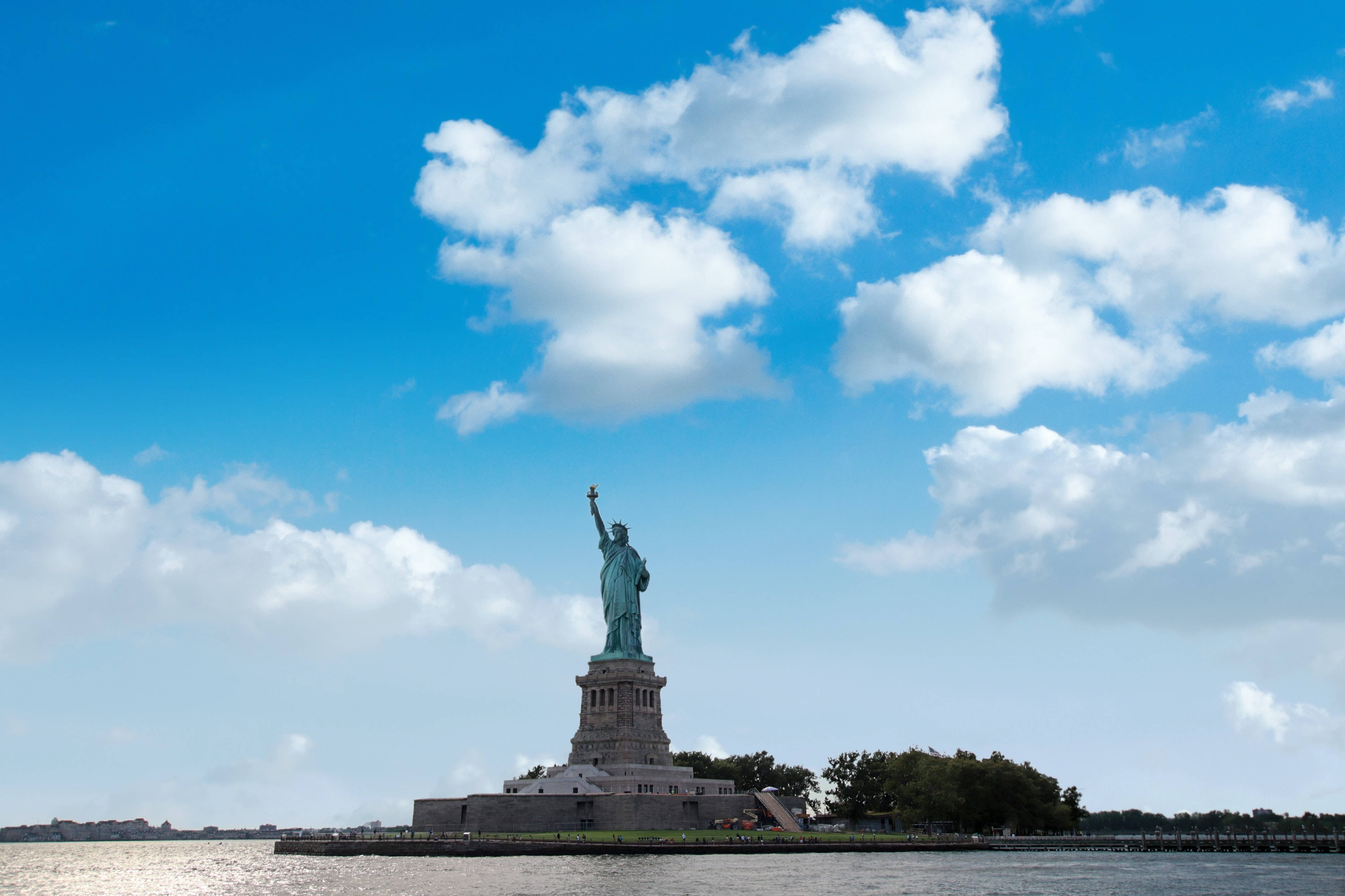 Nyc Aesthetic 桌布 壁紙 — 自由女神像在自由島上高高聳立，天空湛藍，白雲朵朵。