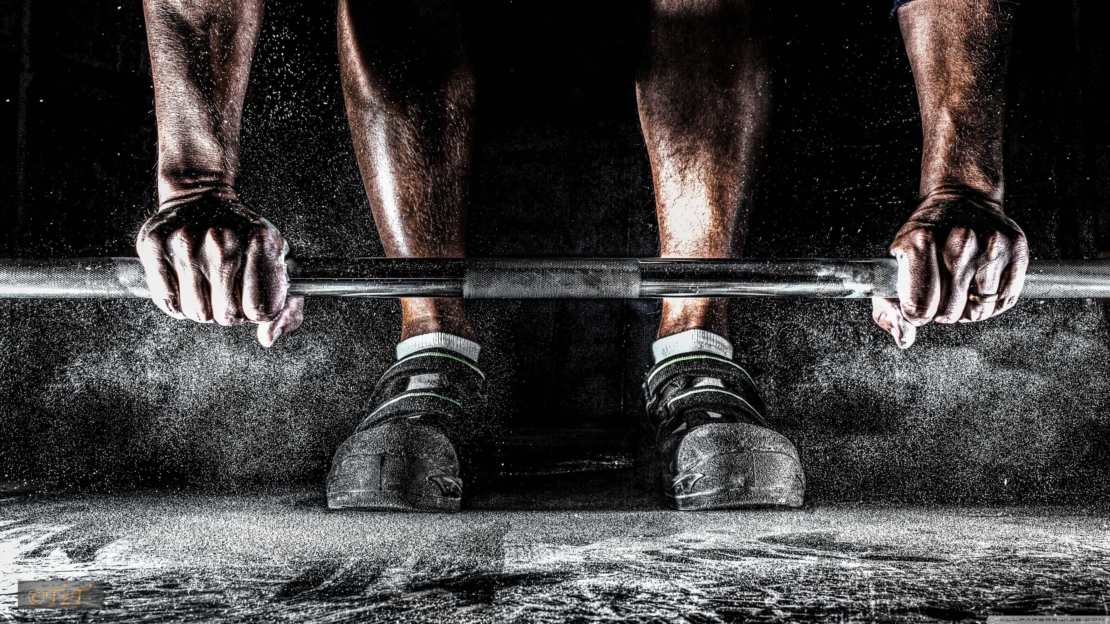 Exercise 桌布 壁紙 — 舉重運動員雙手緊握槓鈴，在昏暗的健身房環境中粉筆灰飛揚的特寫。