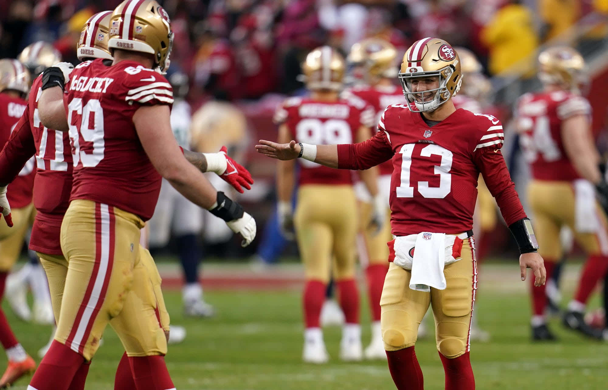 NFL Playoff 桌布 壁紙 — 舊金山49人隊四分衛身穿13號球衣，在陽光明媚的足球場上比賽時做手勢。
