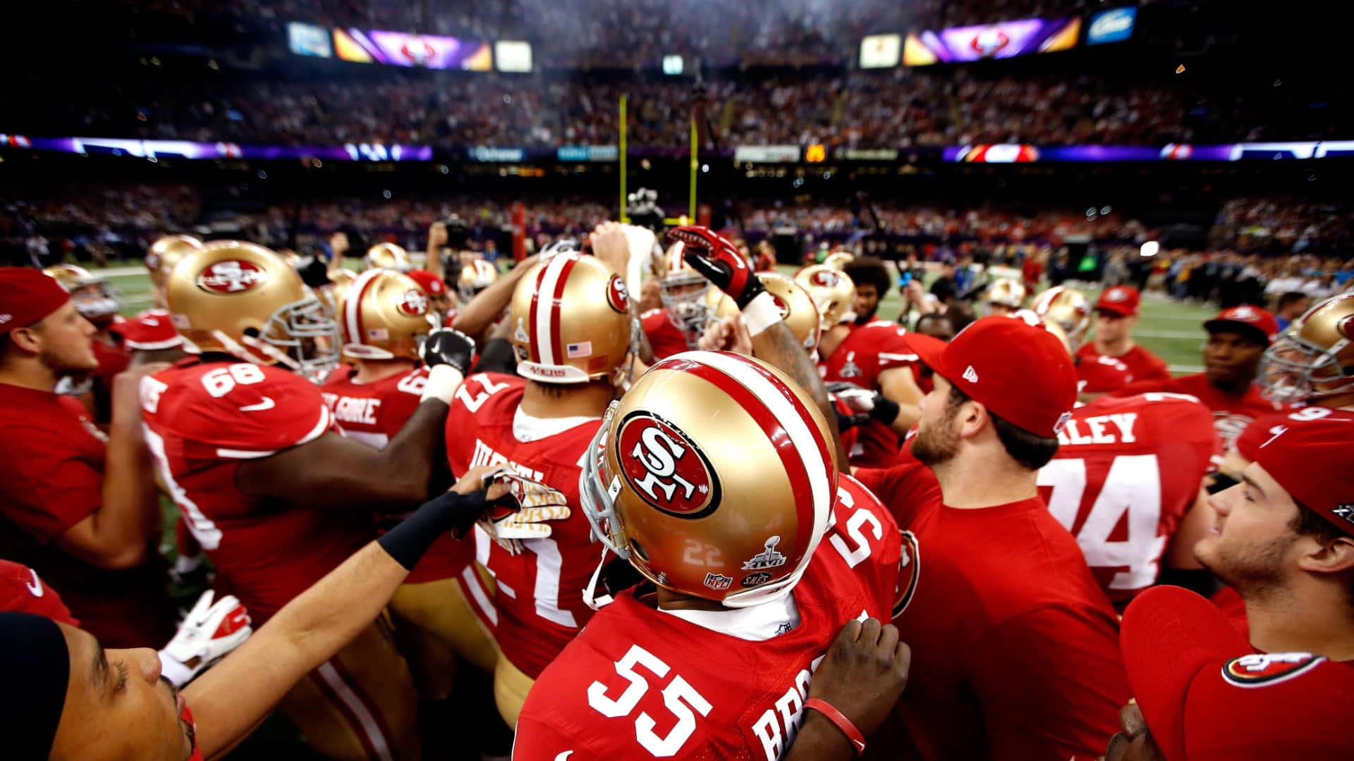 49ers 桌布 壁紙 — 舊金山49人隊的紅色制服美式足球員在球場燈光下一同慶祝。