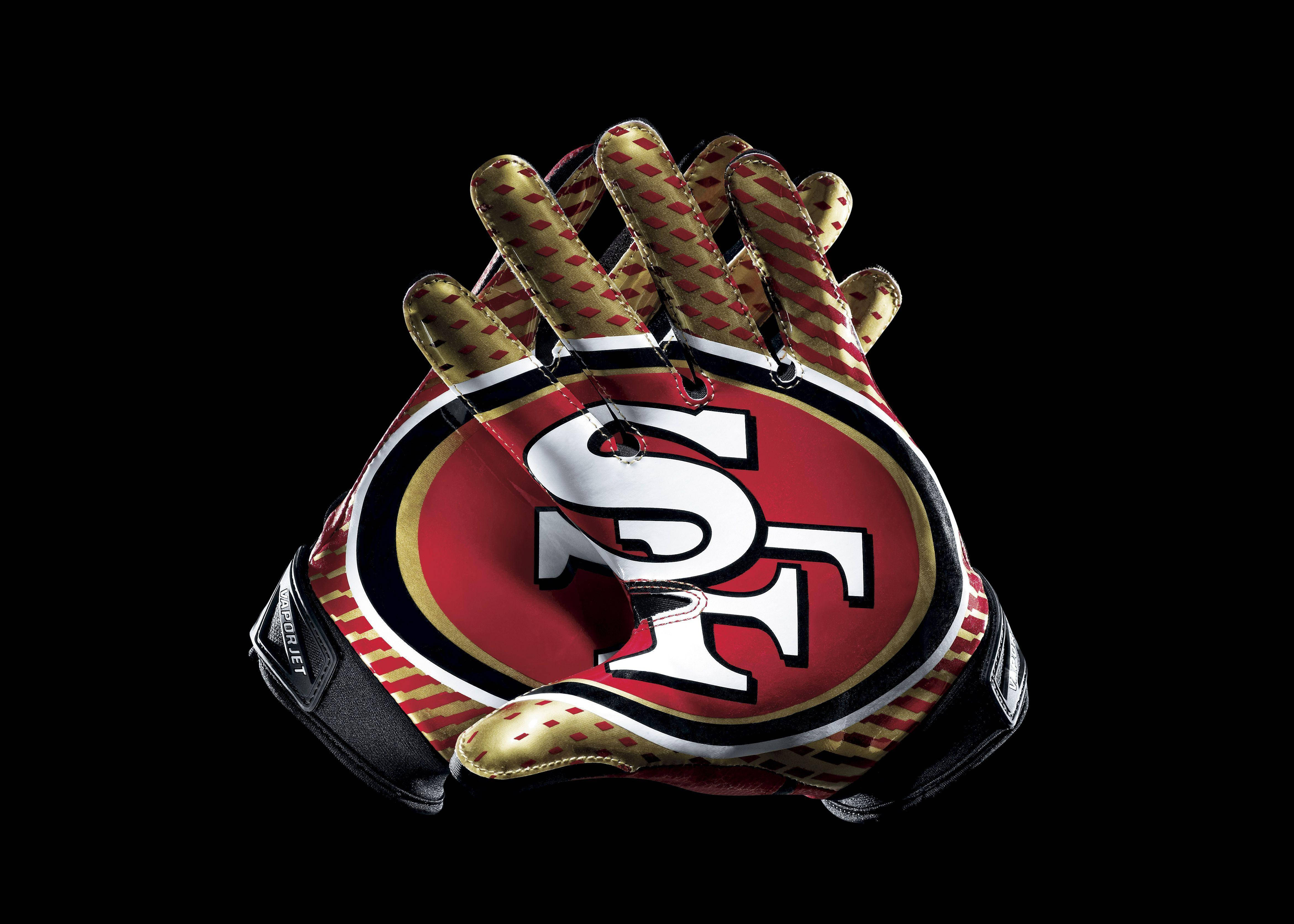49ers 桌布 壁紙 — 舊金山49人隊的足球手套以紅、金、黑色在黑色背景上突出顯示。