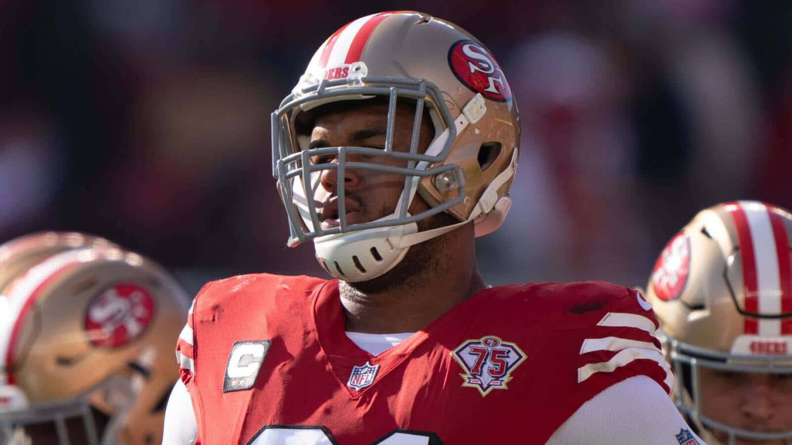 San Francisco 49ers 桌布 壁紙 — 舊金山四九人美式足球員特寫，身穿紅金色球衣、頭盔及面罩，在陽光普照的比賽中。