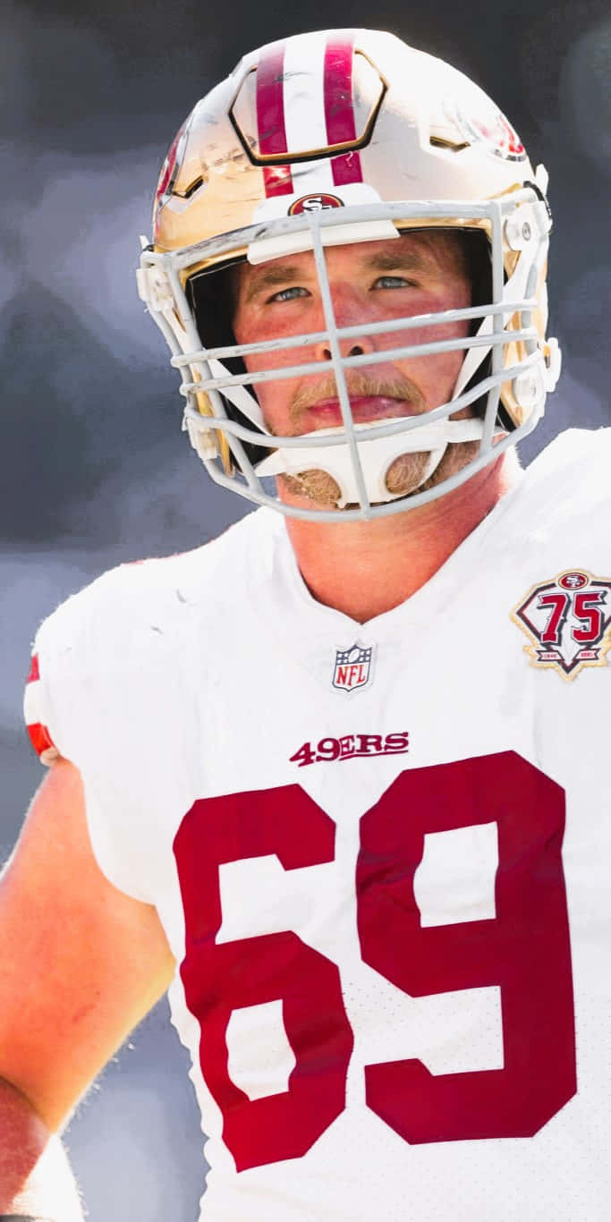 Mike Mcglinchey 桌布 壁紙 — 舊金山四九人美式足球員身穿頭盔及69號球衣，在模糊的球場背景下拍攝的特寫肖像。