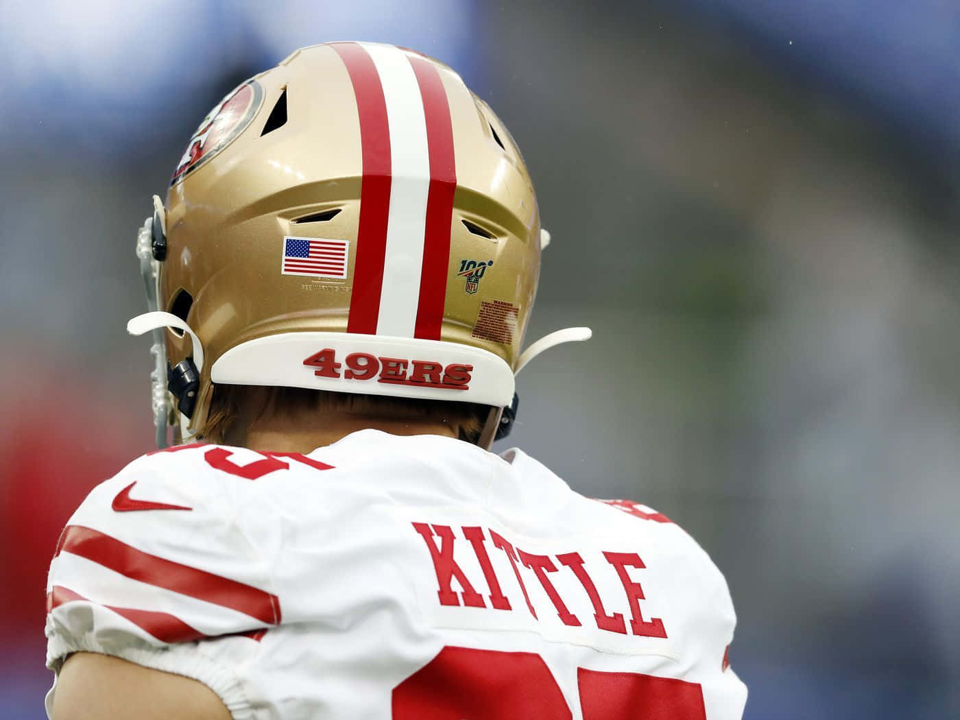 George Kittle 桌布 壁紙 — 舊金山四九人美式足球員近照，戴金色頭盔，穿白色球衣配紅色點綴。
