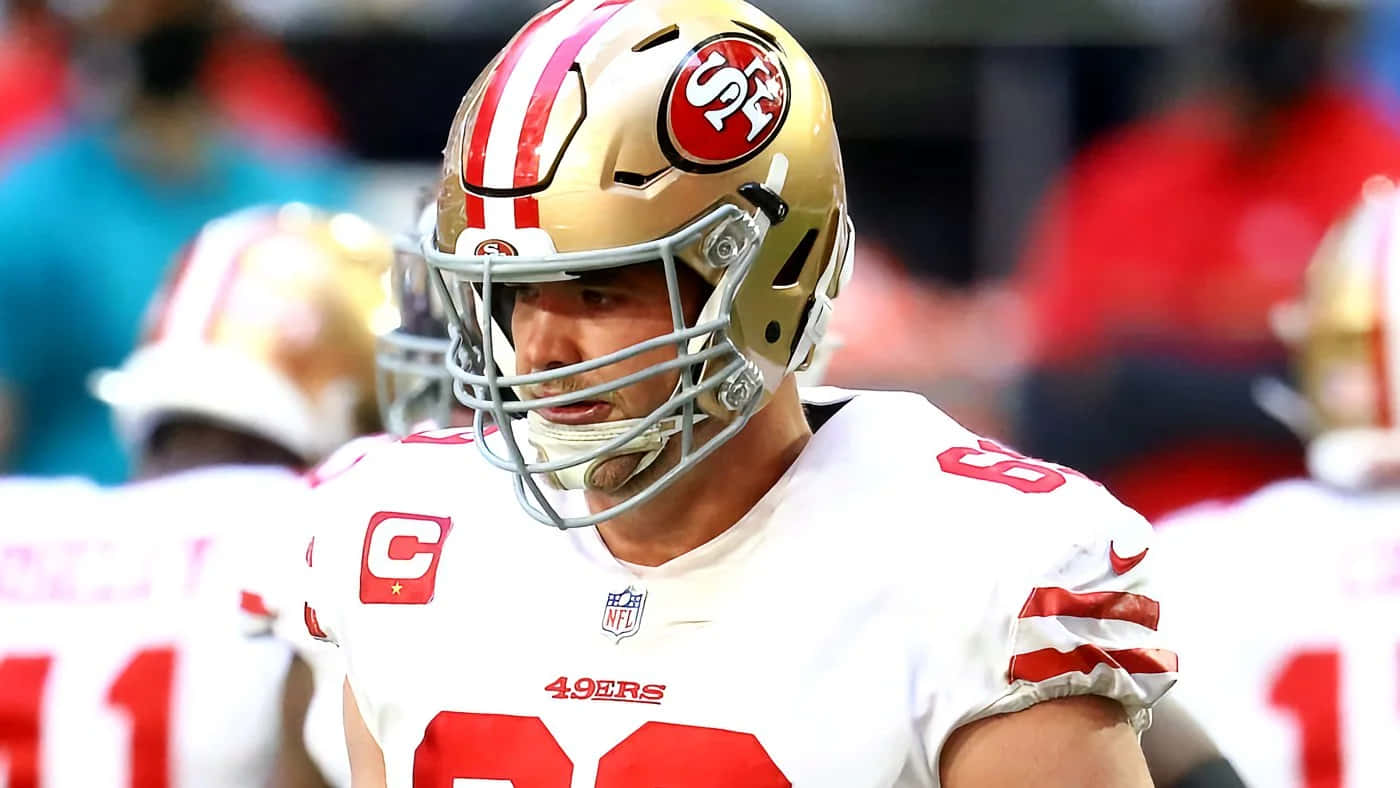 Mike Mcglinchey 桌布 壁紙 — 舊金山四九人美式足球員近距離特寫，戴著金色頭盔，身穿帶有紅色點綴的白色球衣，在球場上。