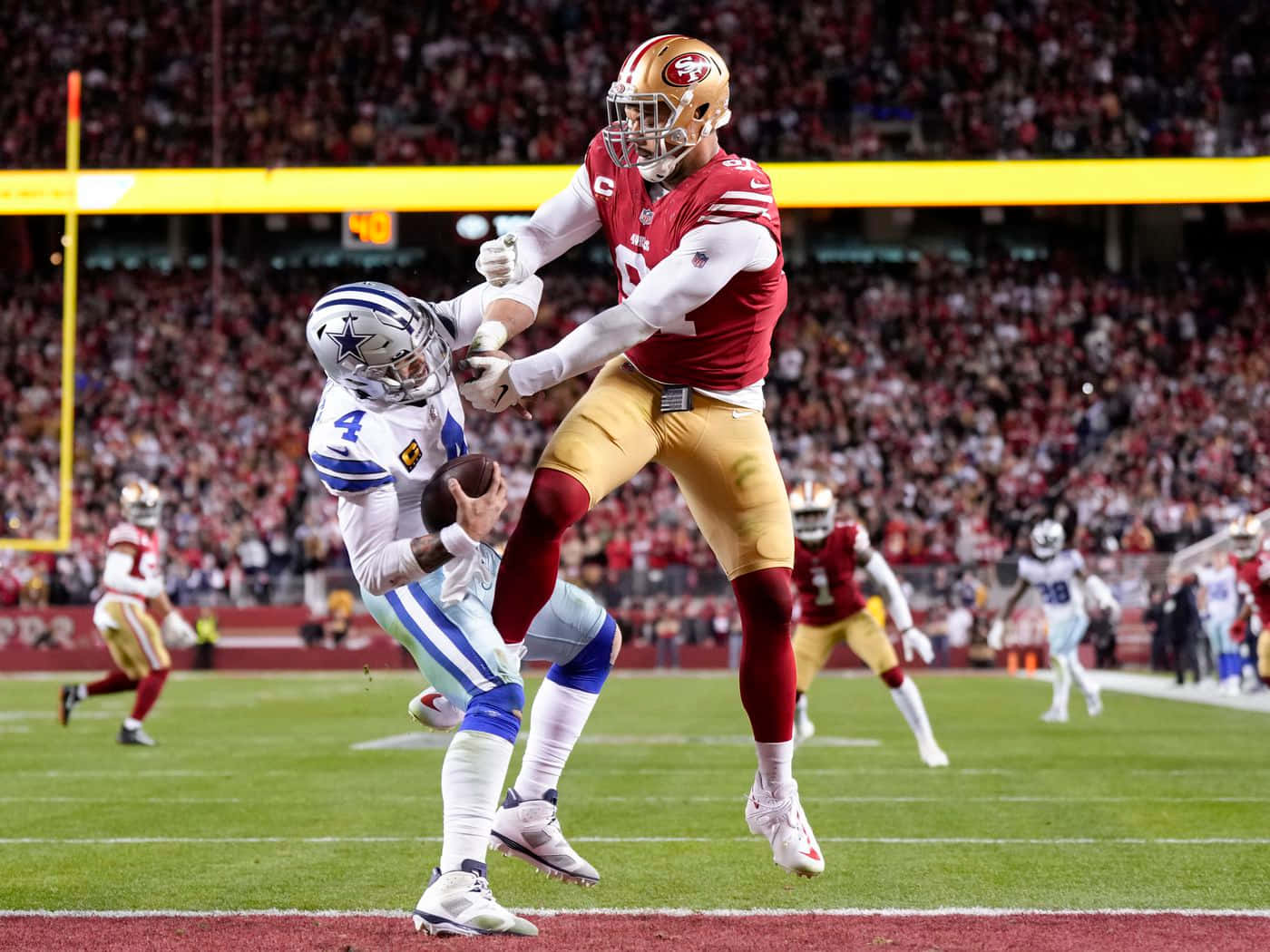San Francisco 49ers 桌布 壁紙 — 舊金山四九人隊的一名防守球員跳起，在擠滿觀眾的球場比賽中擒抱達拉斯牛仔隊的四分衛，完成一次擒殺。