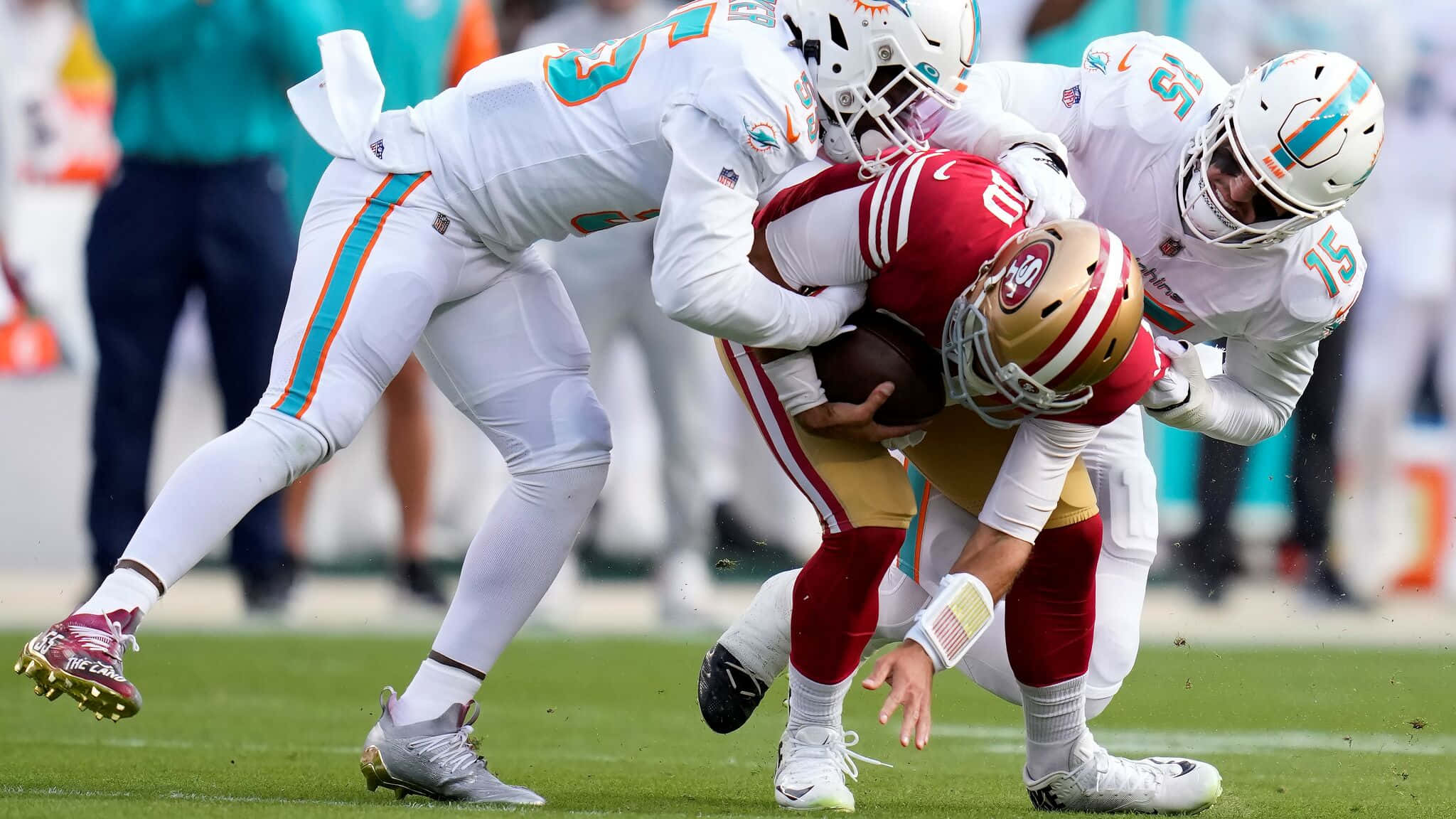 Jimmy Garoppolo 桌布 壁紙 — 舊金山四九人隊的四分衛在充滿活力的綠色足球場上被三名邁阿密海豚隊的防守球員擒抱。
