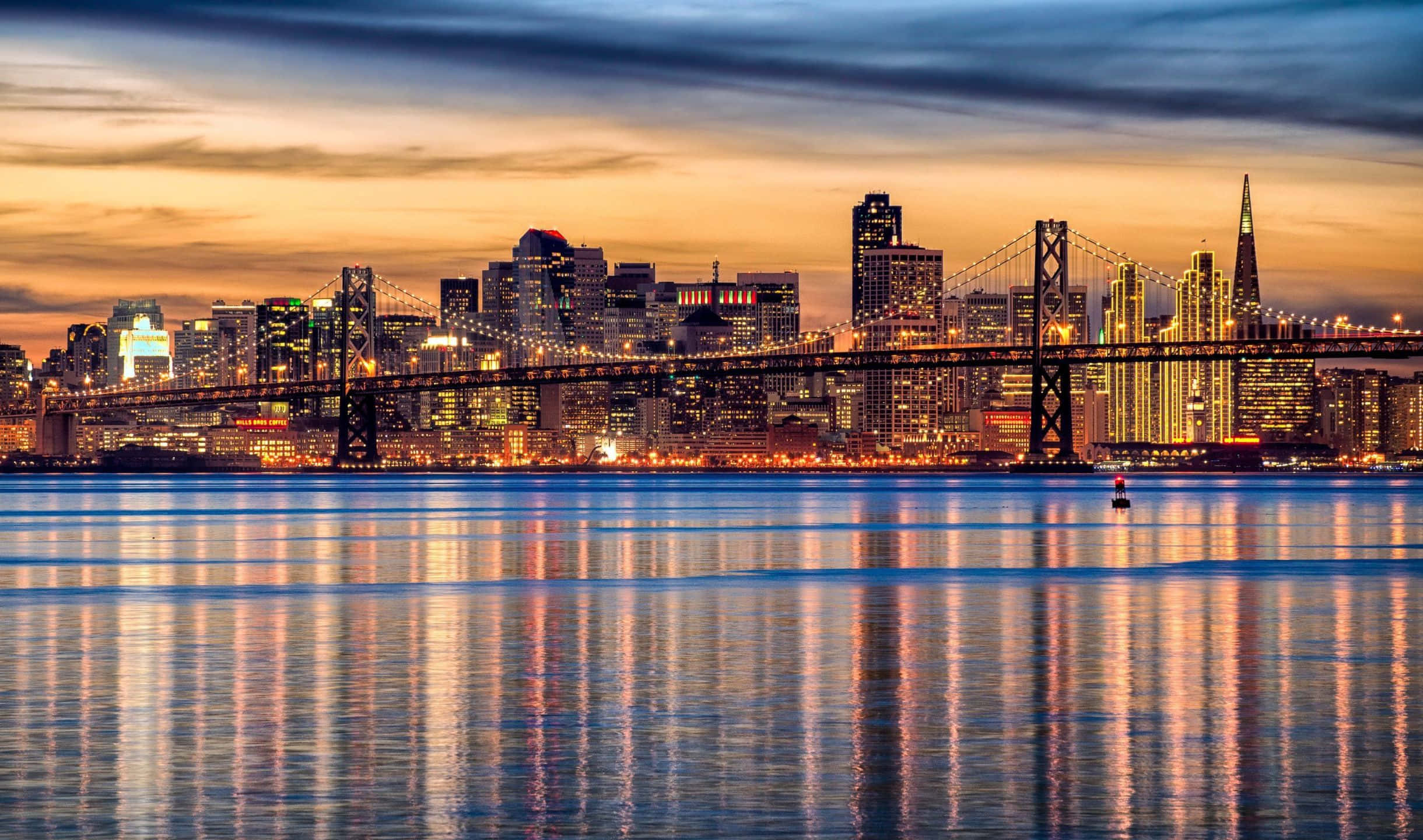 2440x1440 San Francisco 桌布 壁紙 — 舊金山天際線和海灣大橋的黃金時段燈光在黃昏時分在平靜的水面上閃爍。