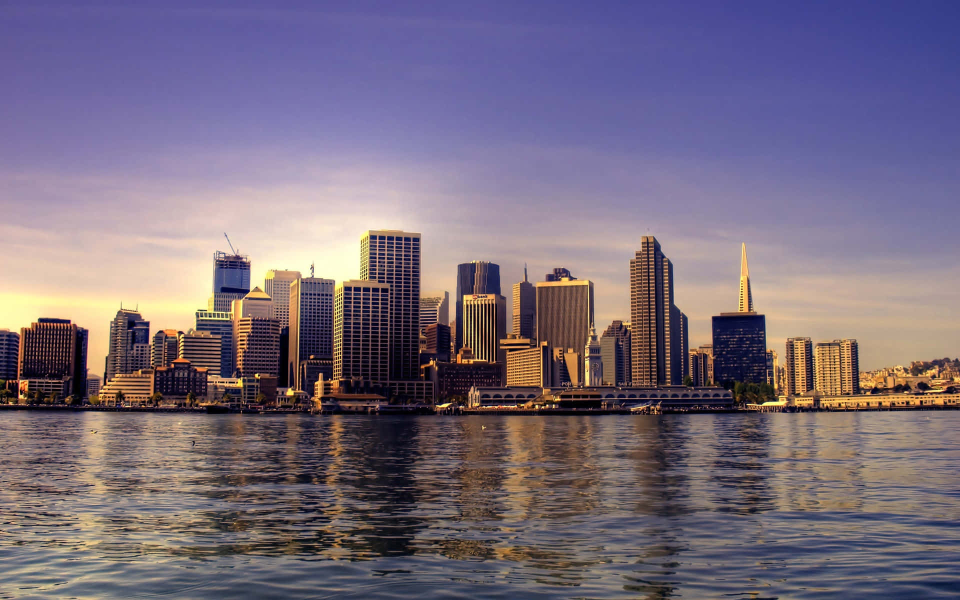 Seattle Skyline 桌布 壁紙 — 舊金山天際線在日落時分，金色光線反射在海灣水面和現代摩天大樓上。