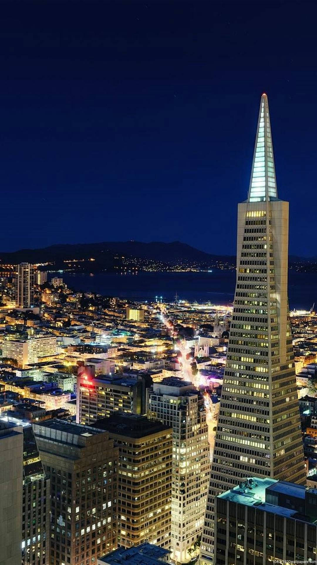 san francisco iPhone 桌布 壁紙 — 舊金山天際線的迷人夜景，明亮的泛美金字塔俯瞰著閃爍的城市景觀和海灣。