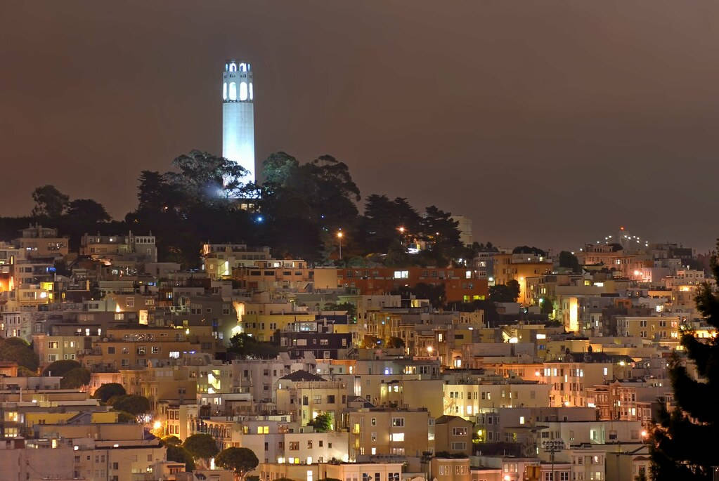 夜空 桌布 壁紙 — 舊金山的夜景，科伊特塔在山頂上發光，周圍是密密麻麻的燈火通明的建築物。