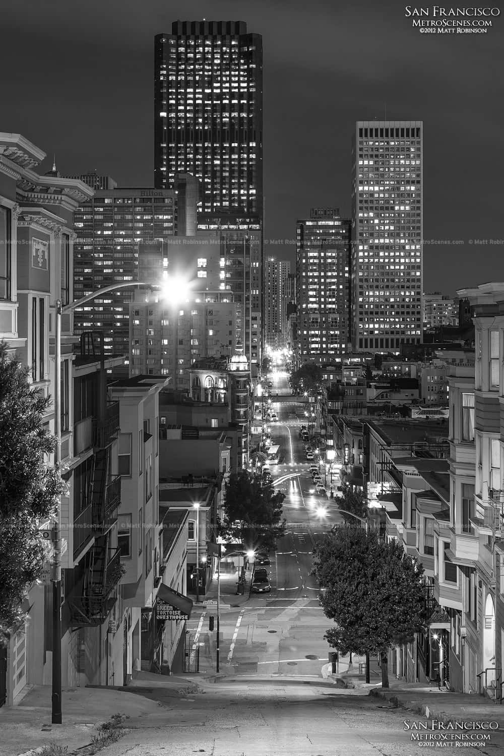 San Francisco Black And White 桌布 壁紙 — 舊金山的黑白夜景，顯示了明亮的摩天大樓和一條有汽車光軌的街道。