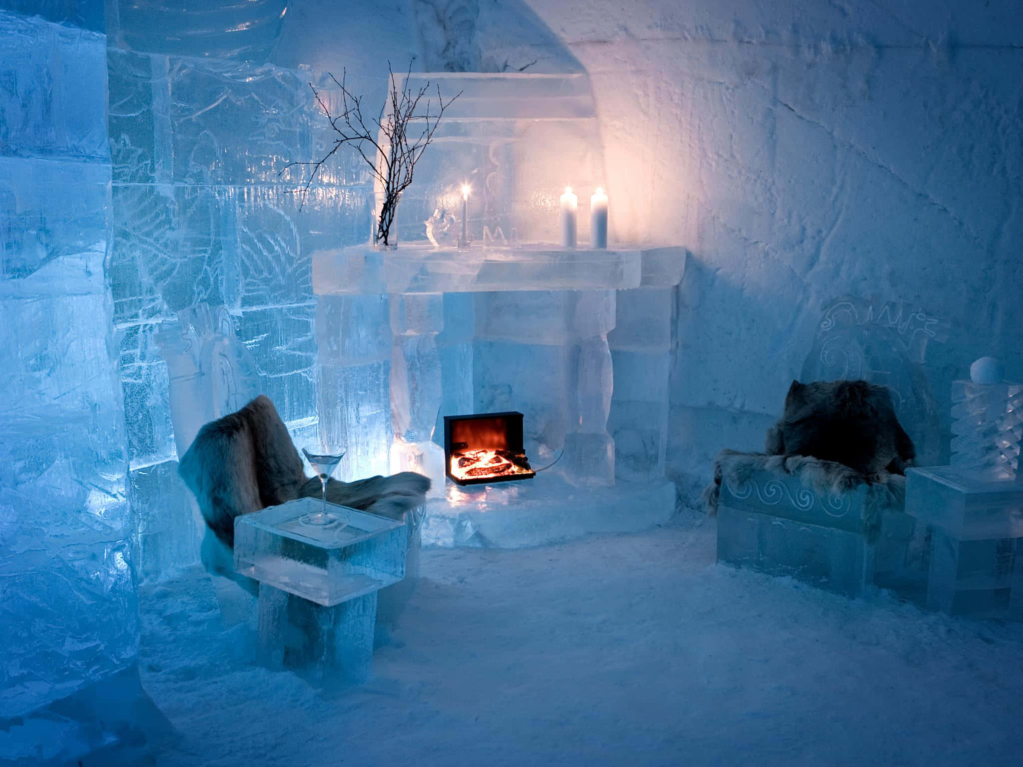 Ice Hotel 桌布 壁紙 — 舒適的冰廳，配有雕刻椅子和壁爐，在涼爽的藍色牆壁上溫暖地發光。