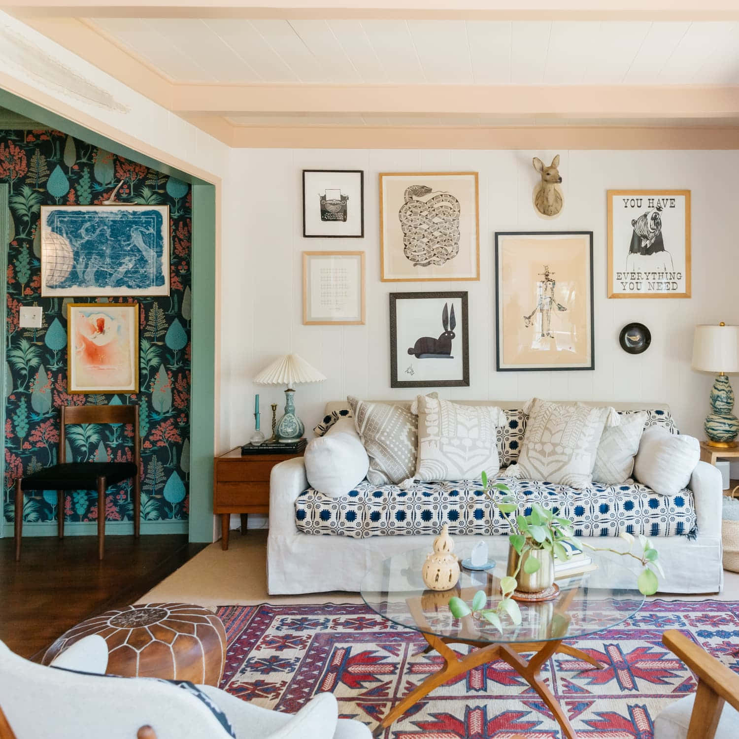 Interior Design 桌布 壁紙 — 舒適的客廳，配有圖案沙發、折衷的牆壁藝術和玻璃咖啡桌下的鮮豔地毯。