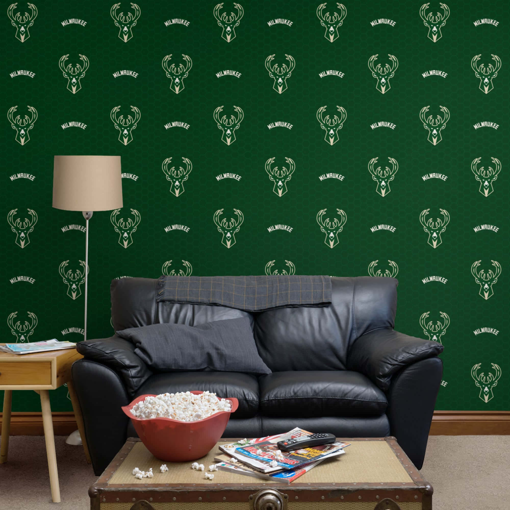 Milwaukee Bucks Logo 桌布 壁紙 — 舒適的客廳，黑色皮革沙發靠著深綠色壁紙，壁紙上印有重複的密爾瓦基公鹿隊標誌。