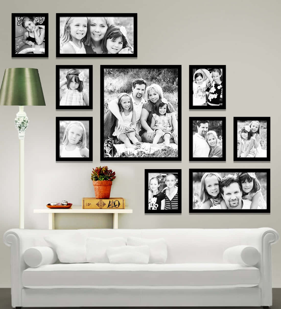 Wall Collage 桌布 壁紙 — 舒適的客廳牆上裝飾著黑色相框中的黑白家庭照片畫廊，位於白色沙發上方。