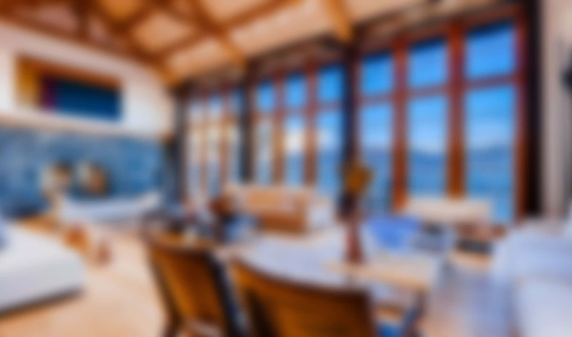 現代舒適的室內設計，配有木樑，透過大窗戶欣賞海景。 — Google Meet 壁紙