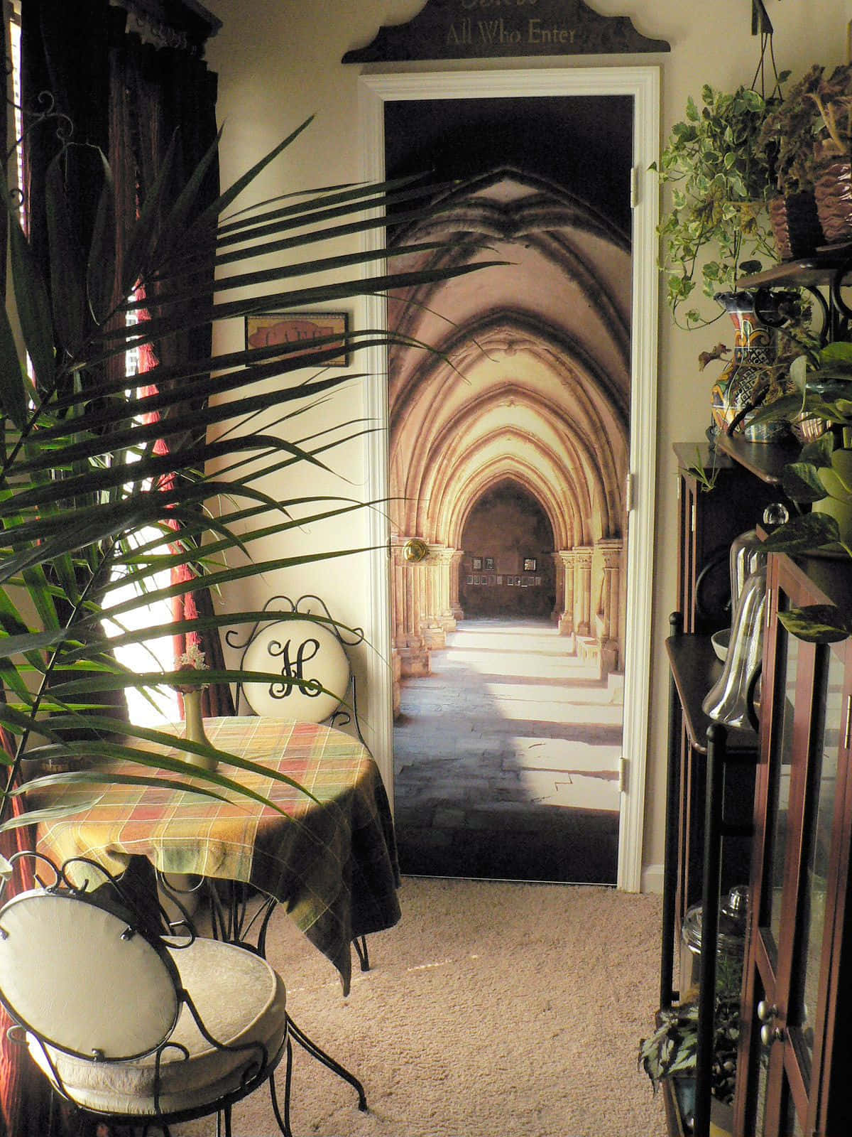 The Hogwarts Charms Corridor 桌布 壁紙 — 舒適的室內走廊有一扇門，裝飾著哥德式大教堂拱門壁畫，兩側有盆栽植物和復古家具。