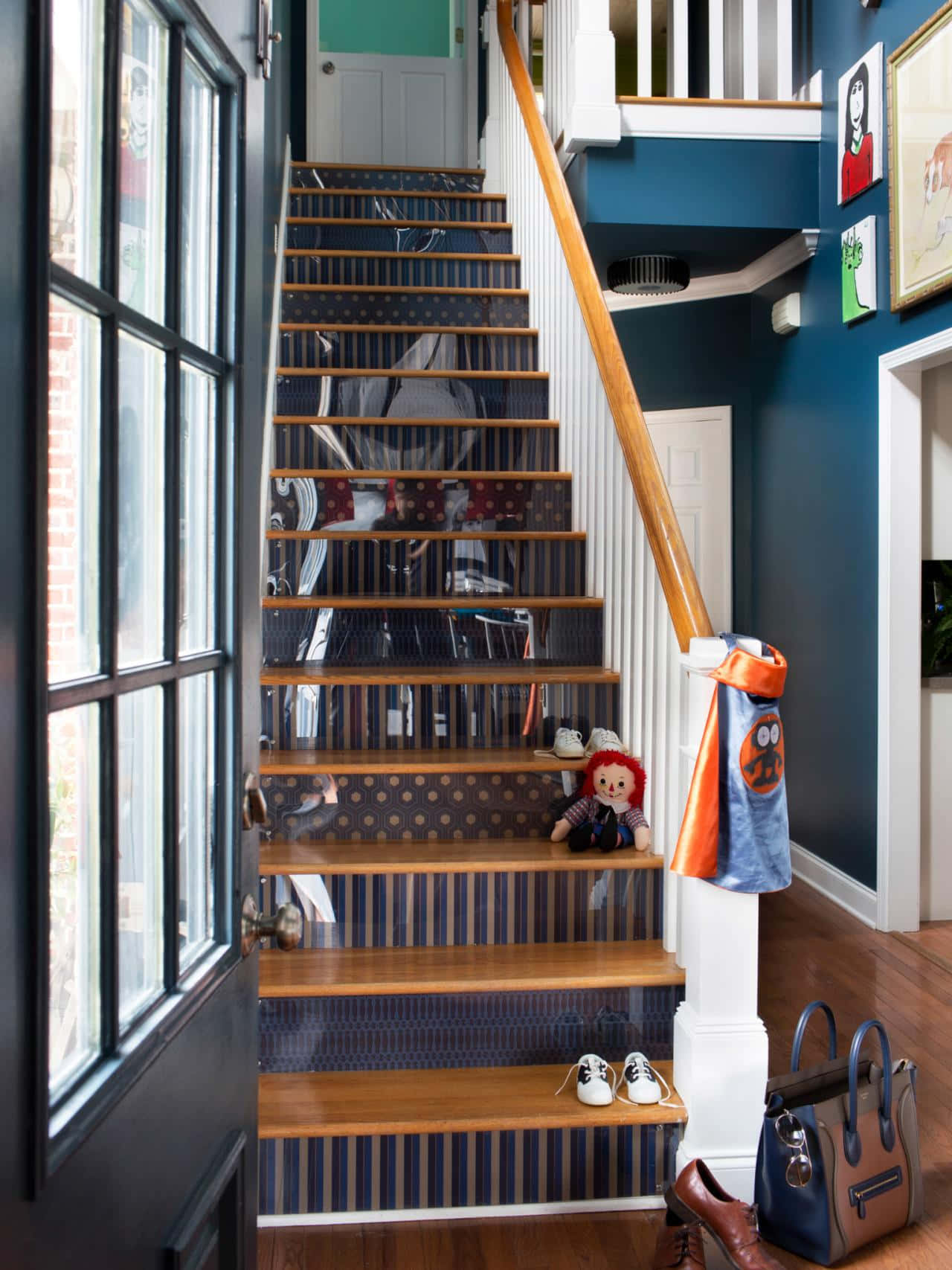 stairs 桌布 壁紙 — 舒適的家居樓梯，配有木質台階、條紋壁紙，以及一個坐在樓梯平台上的娃娃，靠近窗戶和衣帽架。