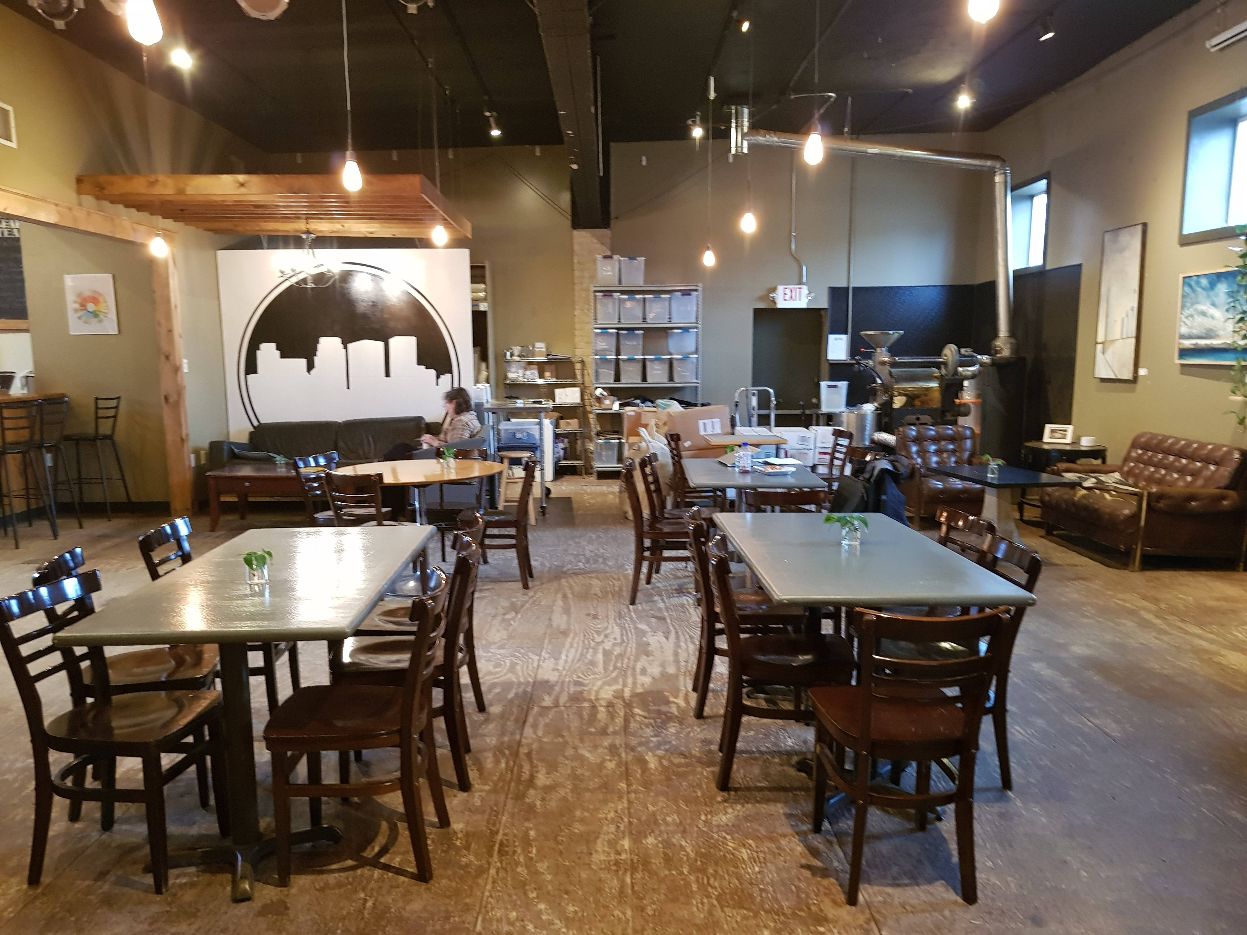 Minneapolis 桌布 壁紙 — 舒適的現代咖啡館，配有木桌、椅子、裸露的橫樑和溫暖的吊燈，在質樸的室內投射出柔和的光芒。