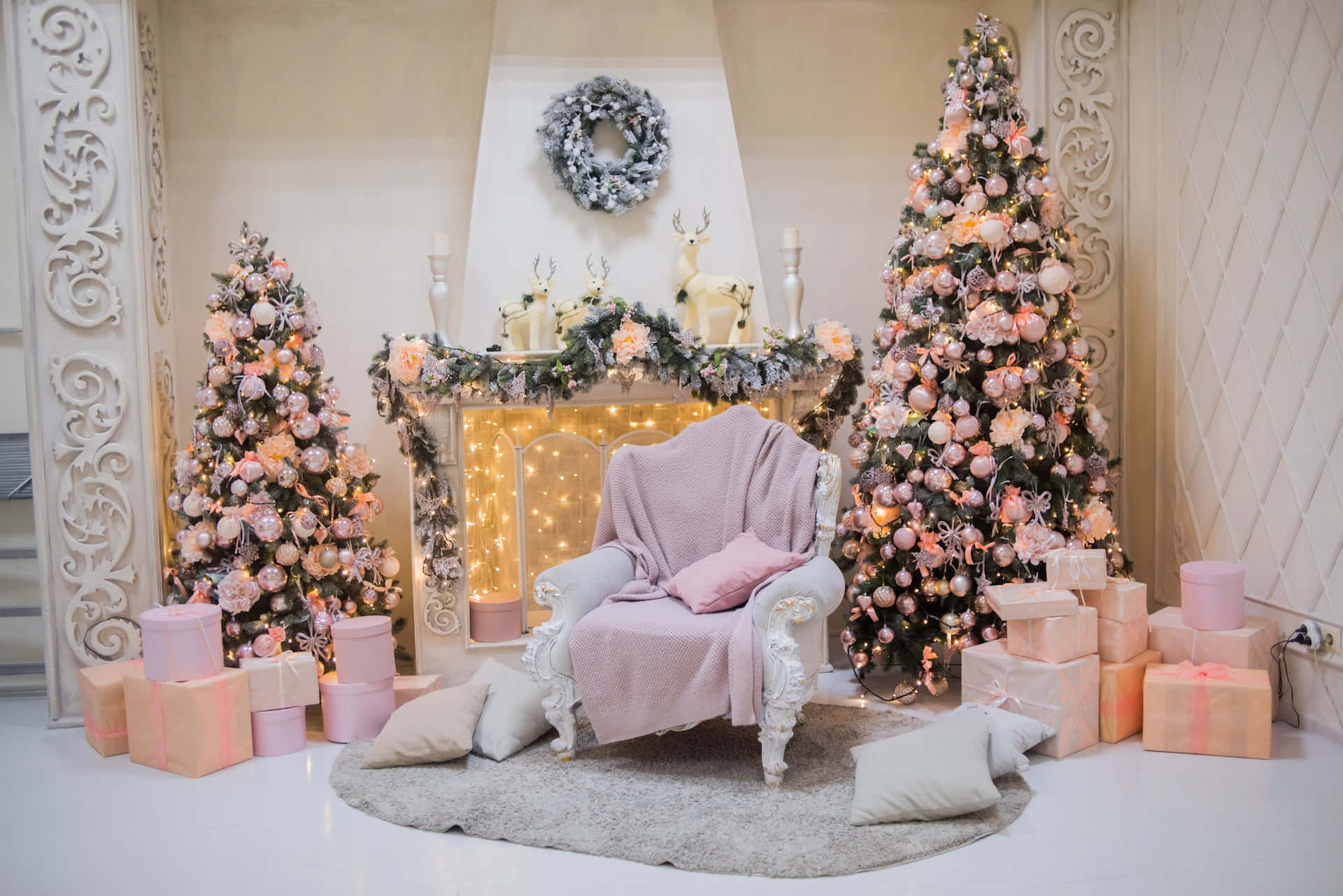 Aesthetic Christmas Tree 桌布 壁紙 — 舒適的粉紅和白色聖誕場景，有華麗的樹木、閃爍的燈光，以及壁爐旁的一張毛絨扶手椅。