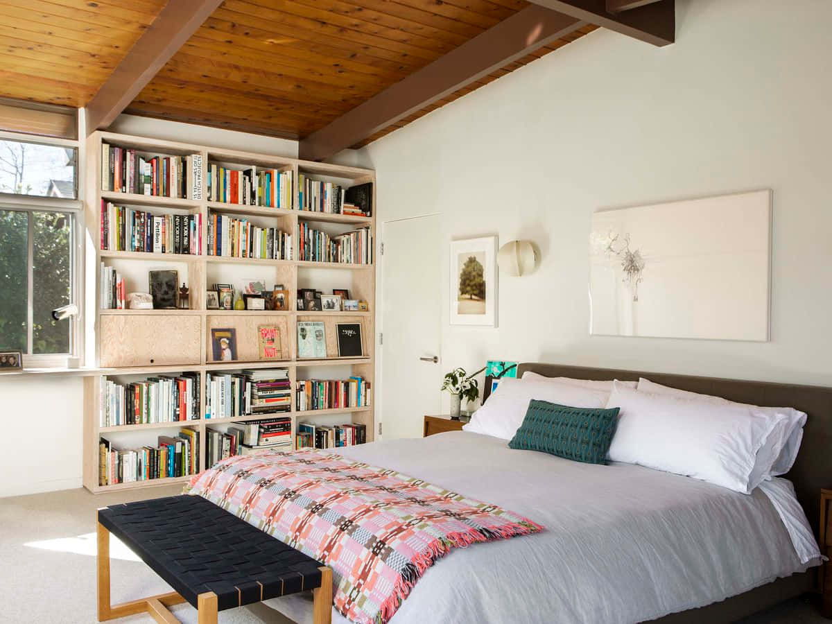 Bedroom 桌布 壁紙 — 舒適的臥室，設有木樑天花板、裝滿書籍的書架，以及一張鋪有彩色圖案床罩的床。