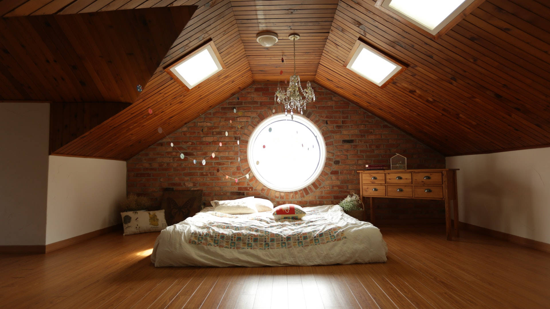 bed 桌布 壁紙 — 舒適的閣樓臥室，配有木地板和天花板、磚牆，以及一個讓明亮自然光線透入的大圓窗。