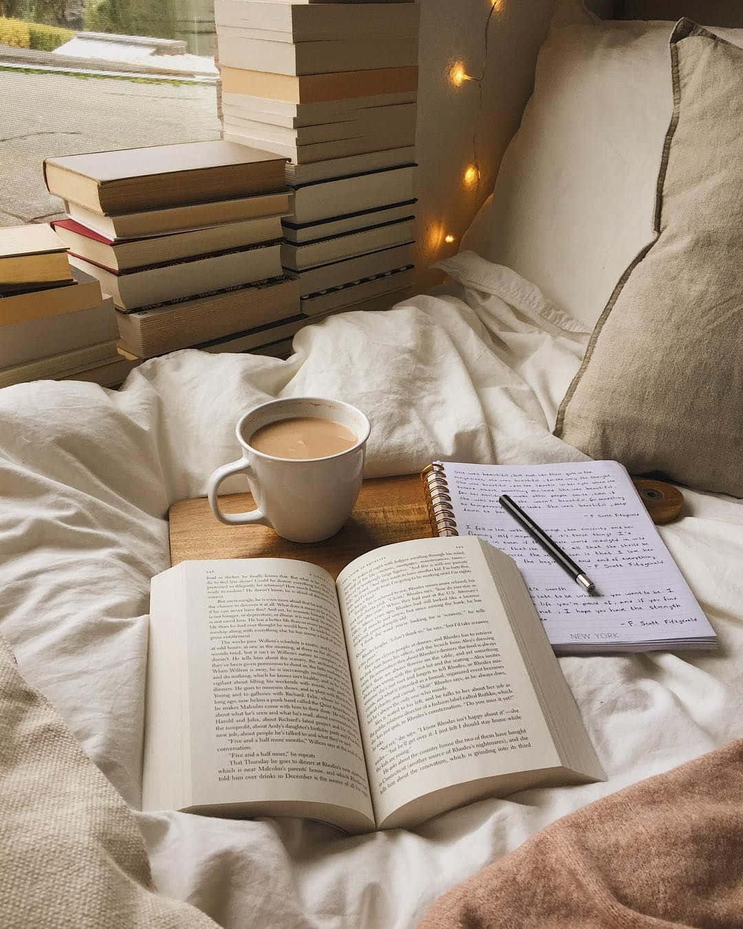 Aesthetic Book 桌布 壁紙 — 舒適的閱讀角落，床上放有打開的書本、咖啡杯和書堆，並有仙女燈裝飾。